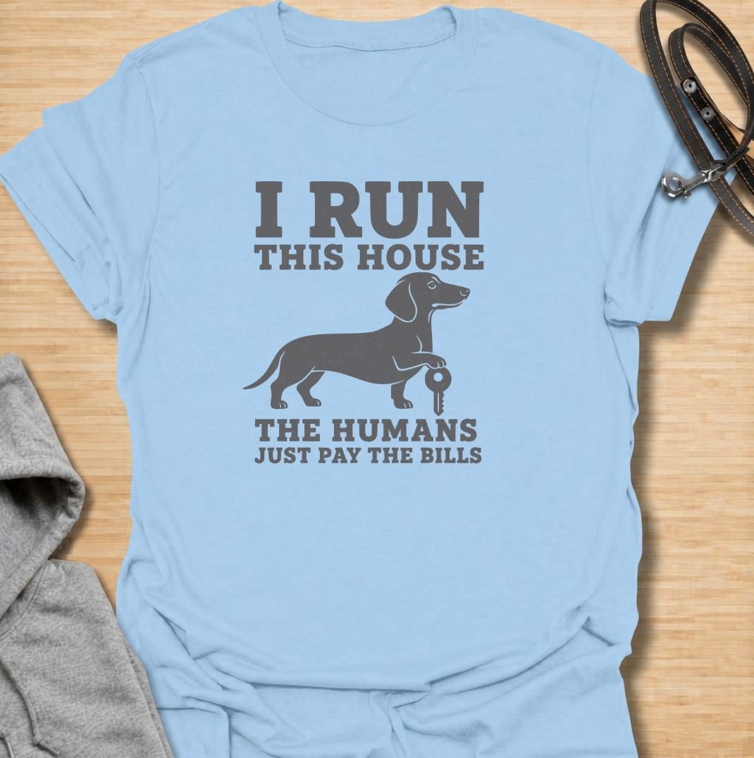I run this house—the humans just pay the bills. A funny dachshund T-shirt for owners whose confident sausage dog is clearly in charge.