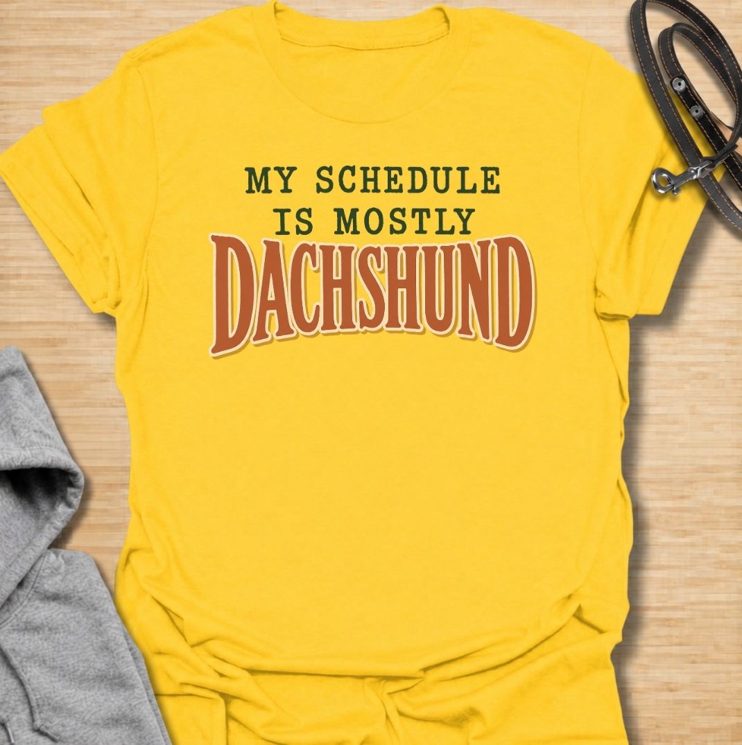 A funny dachshund T-shirt for anyone whose daily plans somehow revolve around their favorite little dog. Featuring the phrase “My Schedule Is Mostly Dachshund” in bold vintage-inspired typography, this design is simple, punchy, and easy to wear. Perfect for dachshund moms, dachshund dads, sausage dog owners, and anyone whose calendar is permanently shaped around walks, cuddles, and dachshund demands. A fun everyday tee for dog lovers who know exactly who really controls the schedule.