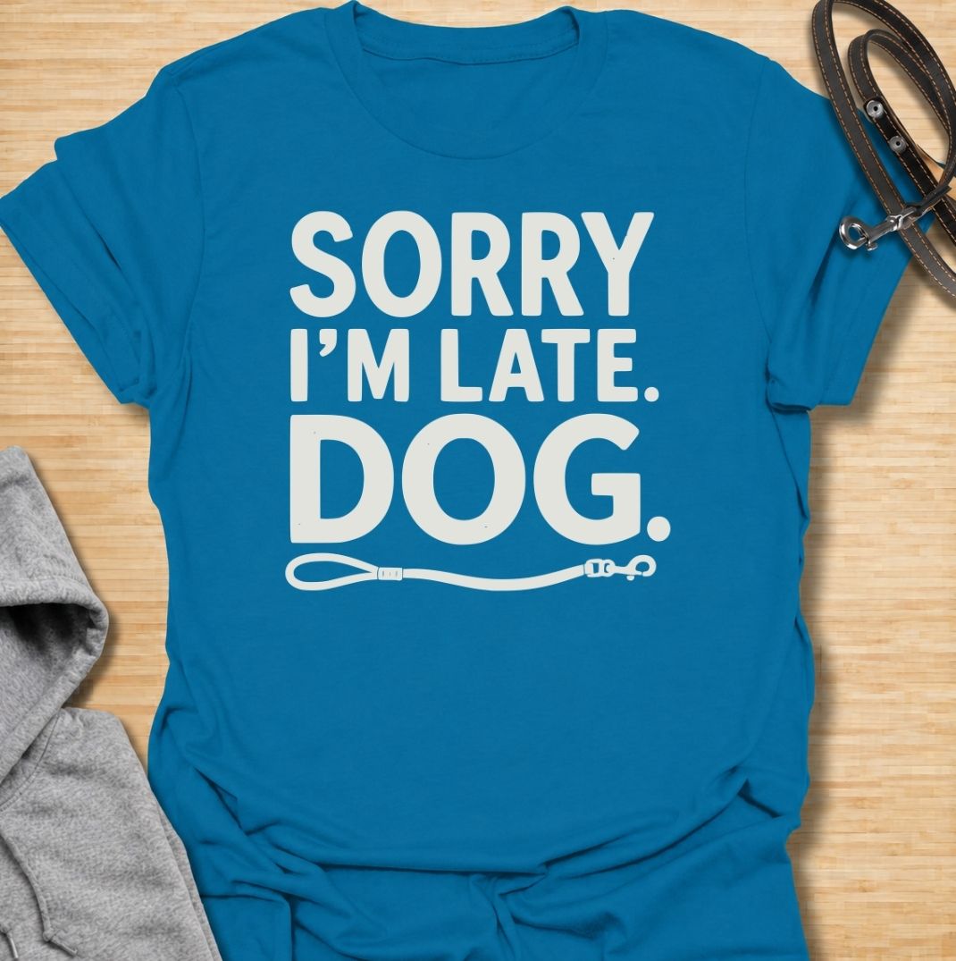 A funny dog T-shirt for anyone whose schedule is regularly dictated by walks, sniffing stops, and a four-legged companion. Featuring the phrase “Sorry I’m Late. Dog.” with a simple leash graphic, this design delivers dry, relatable dog-owner humor in a clean text-based style. Perfect for dog moms, dog dads, rescue dog owners, and anyone who has ever blamed their lateness on the dog. A playful everyday tee for fans of funny dog sayings, pet parent humor, and general dog lover gifts.
