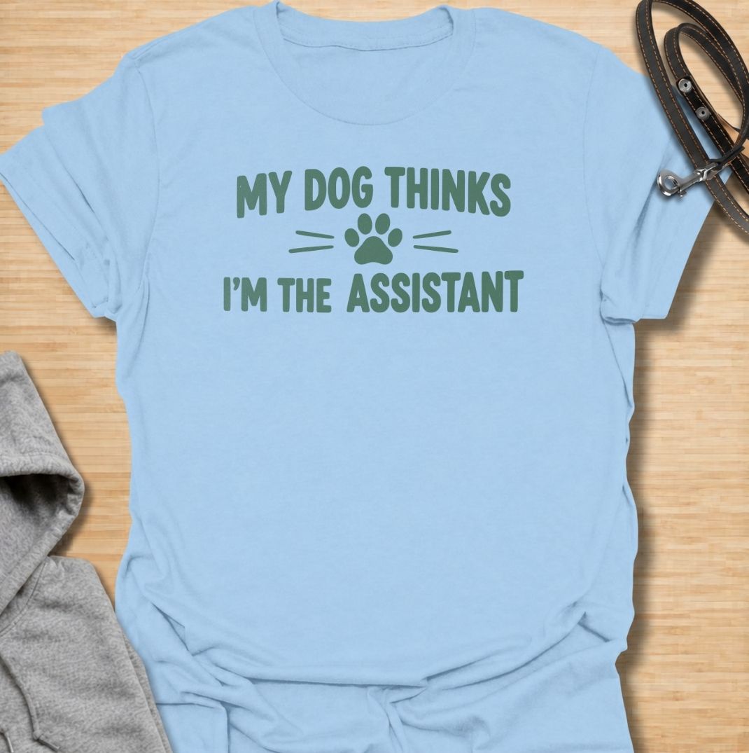 A funny dog T-shirt for anyone who knows their dog is really the one running the household. Featuring the phrase “My Dog Thinks I’m the Assistant” with a simple paw print graphic, this clean text-based design captures everyday dog-owner life with relatable humor. Perfect for dog moms, dog dads, rescue dog owners, and anyone whose pet expects first-class service at all times. A playful everyday tee for fans of funny dog sayings, pet parent humor, and general dog lover gifts.