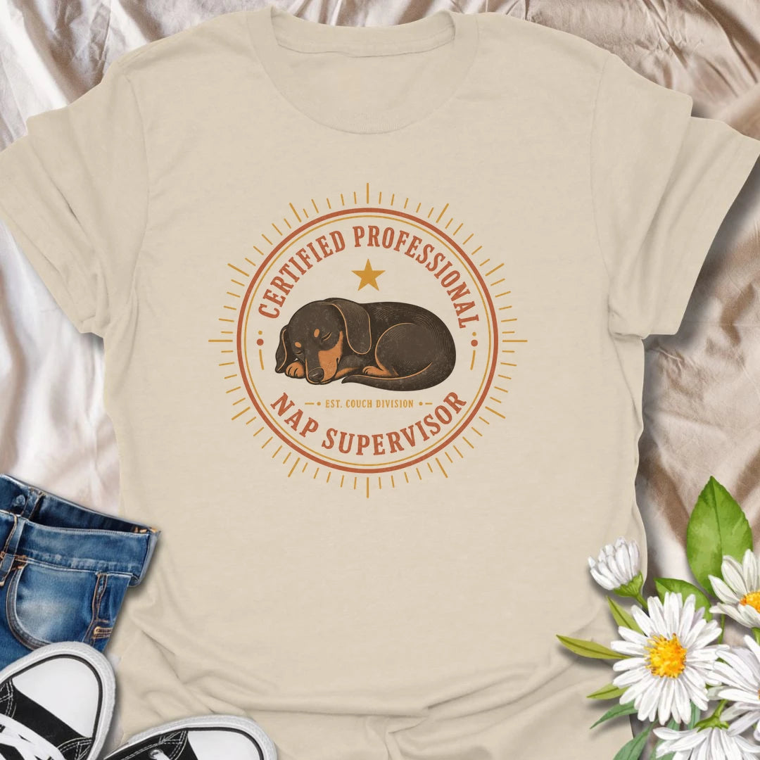 Every couch needs a certified professional nap supervisor, and dachshunds are uniquely qualified. This vintage badge-style T-shirt celebrates the sausage dog’s impressive dedication to sleeping and household supervision. A cozy, funny gift for dachshund owners and devoted doxie fans.