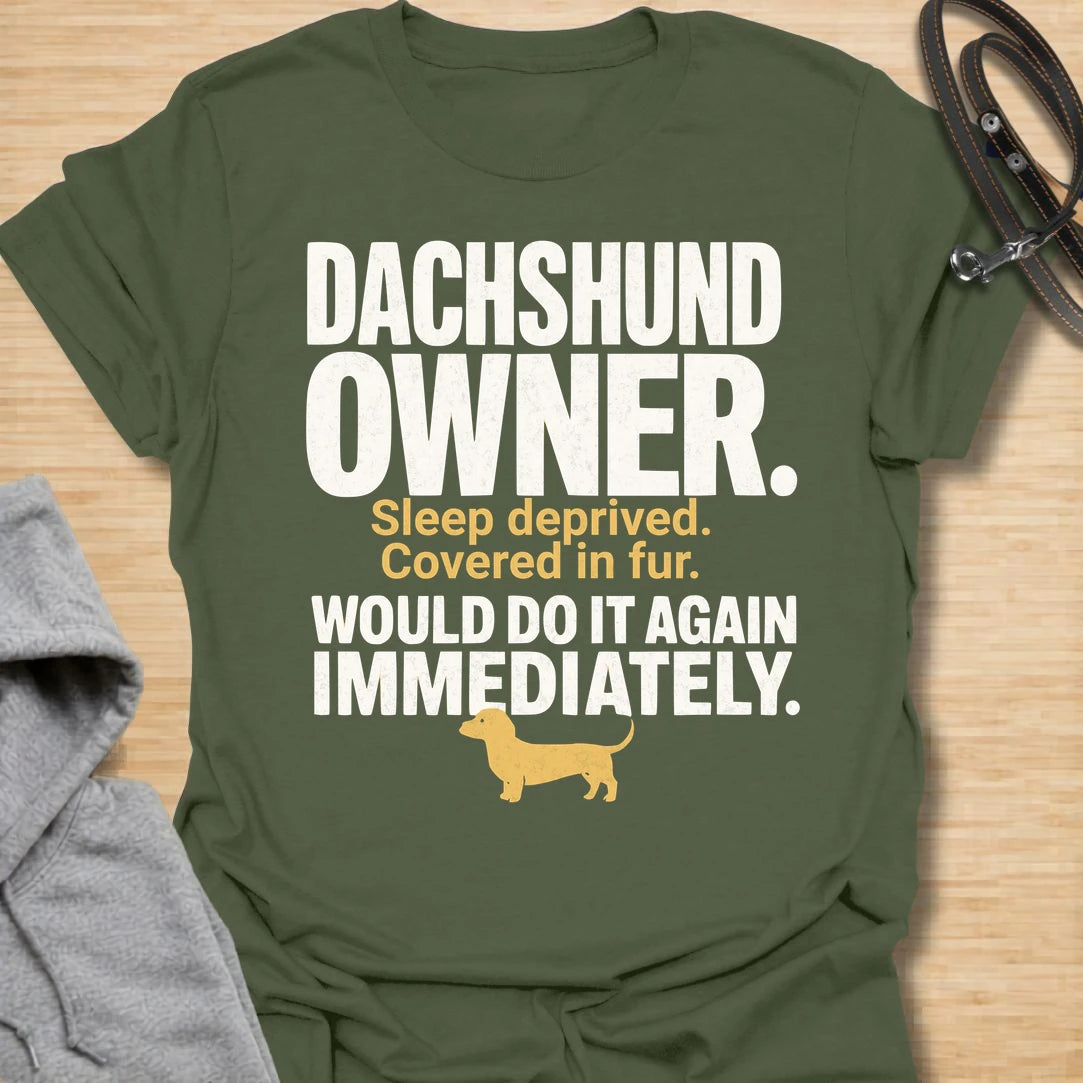 This Dachshund Owner t-shirt is made for doxie lovers who know the tiny legs come with big opinions, endless fur, and questionable sleep. Featuring bold distressed typography, a small dachshund silhouette, and the funny phrase Sleep Deprived. Covered In Fur. Would Do It Again Immediately., this design has a relatable dog-parent feel that dachshund owners will instantly understand. Perfect for dachshund moms, dachshund dads, wiener dog fans, rescue dog lovers, and anyone who knows life with a dachshund is ch