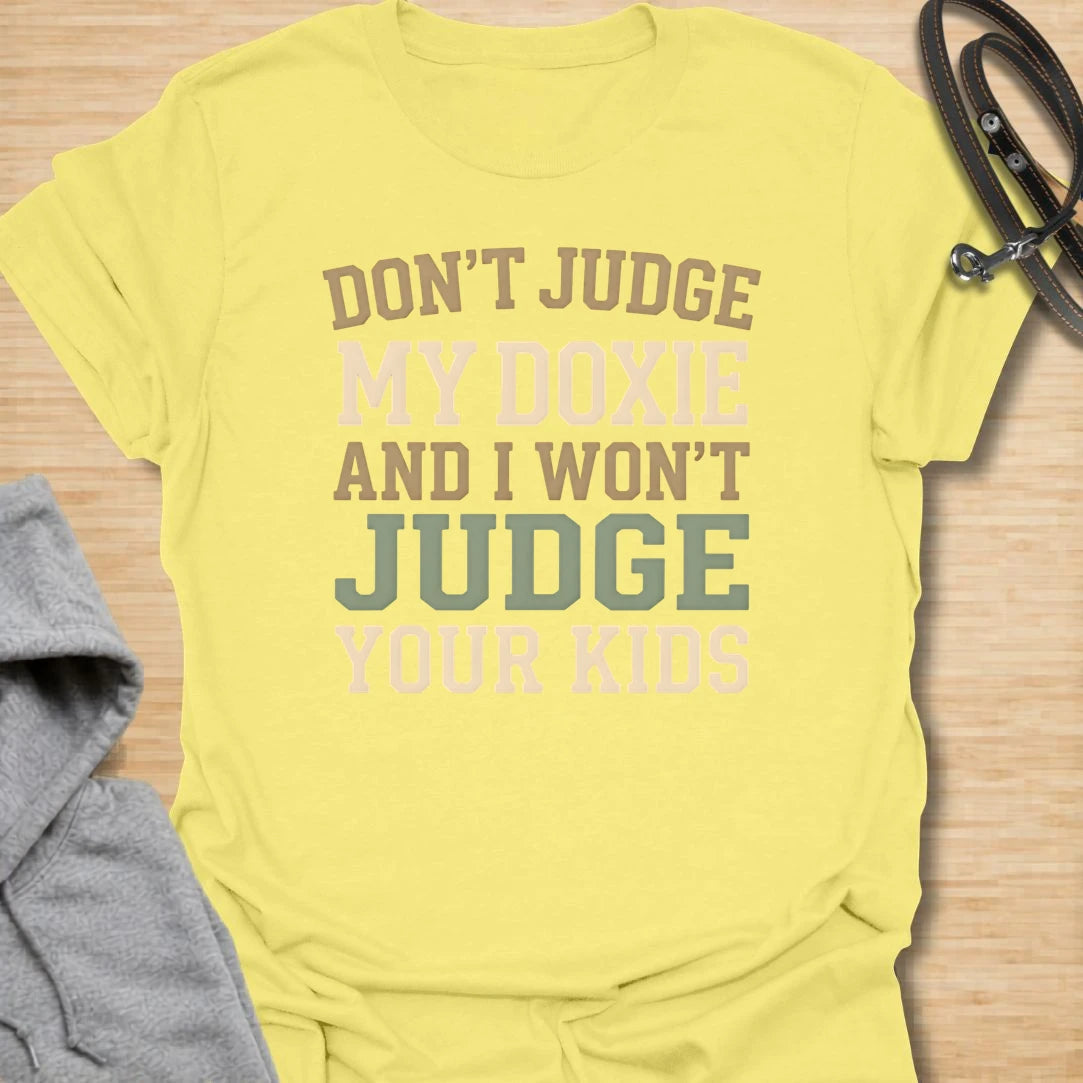This Don’t Judge My Doxie t-shirt is made for dachshund lovers who know their little long dog may have opinions, attitude, and questionable manners, but judgment is a two-way street. Featuring bold text-only typography with the funny phrase Don’t Judge My Doxie And I Won’t Judge Your Kids, this design has a sarcastic dog-parent feel that doxie owners will instantly understand. Perfect for dachshund moms, dachshund dads, wiener dog fans, rescue dog lovers, and anyone who will always defend their doxie first.