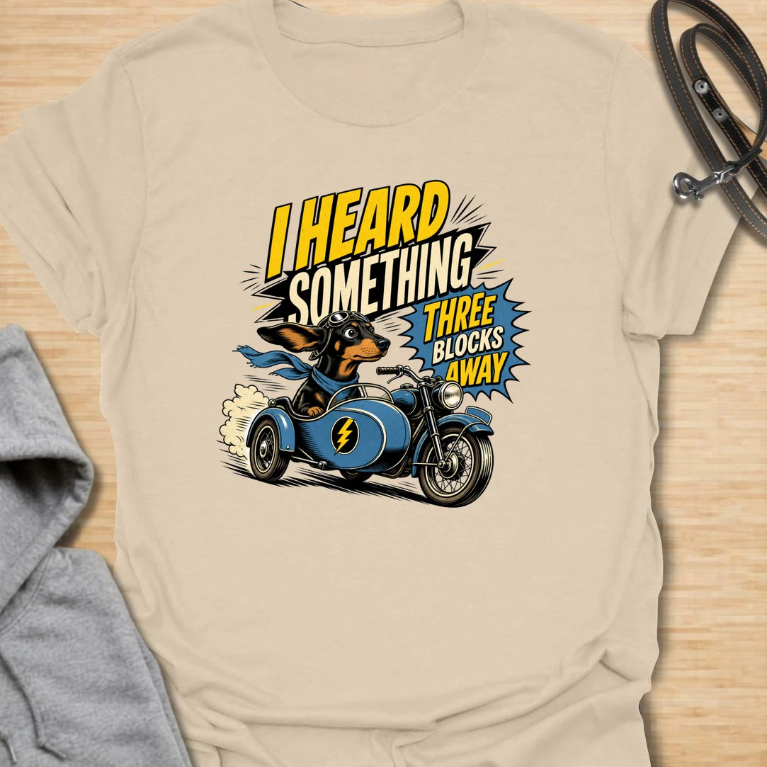 Three Blocks Away t-shirt for dachshund lovers who know their little dog hears absolutely everything. This funny design features a speedy wiener dog racing in a vintage car with bold retro lettering and chaotic doxie energy. Perfect for dachshund moms, doxie dads, sausage dog owners, and anyone living with a tiny dog who is always on neighborhood patrol.