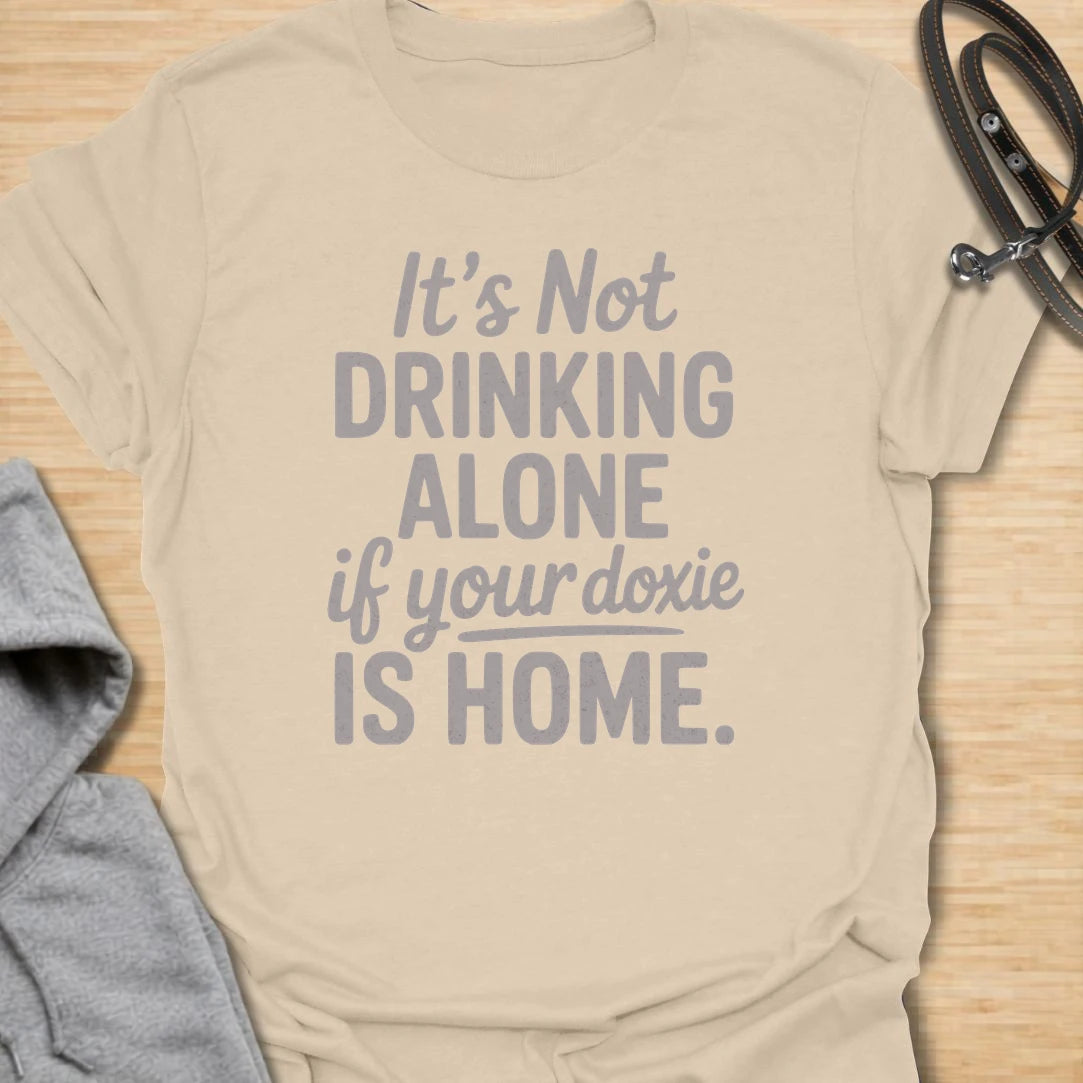 Drinking Alone Doxie t-shirt for dachshund owners who know a doxie at home means you are never really drinking alone. This funny text design says “It’s Not Drinking Alone If Your Doxie Is Home,” making it perfect for wine lovers, dog moms, and sausage dog fans. A fun gift for dachshund lovers who enjoy cozy nights in with their favorite four-legged companion.