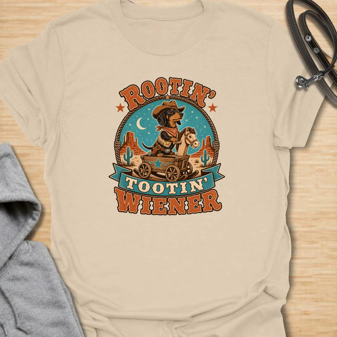 Rootin Tootin Wiener t-shirt for dachshund lovers who enjoy funny western dog humor and chaotic sausage dog energy. This playful design features a cowboy-style dachshund riding in a wagon with bold vintage rodeo lettering. Perfect for doxie moms, wiener dog fans, sausage dog owners, and anyone who loves a small dog with big outlaw attitude.