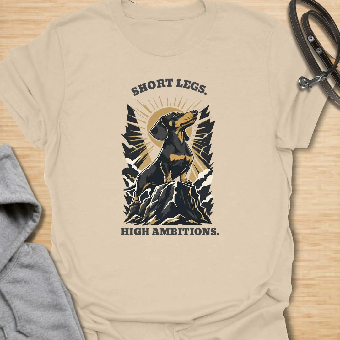 Short Legs High Ambitions t-shirt for dachshund lovers who know tiny legs never mean tiny confidence. This bold mountain-style design features a proud dachshund standing tall with dramatic vintage outdoor energy. A great gift for dachshund moms, dachshund dads, hikers, dog lovers, and anyone who loves a determined little sausage dog. Perfect for everyday wear, dog walks, casual weekends, or showing off big doxie attitude.