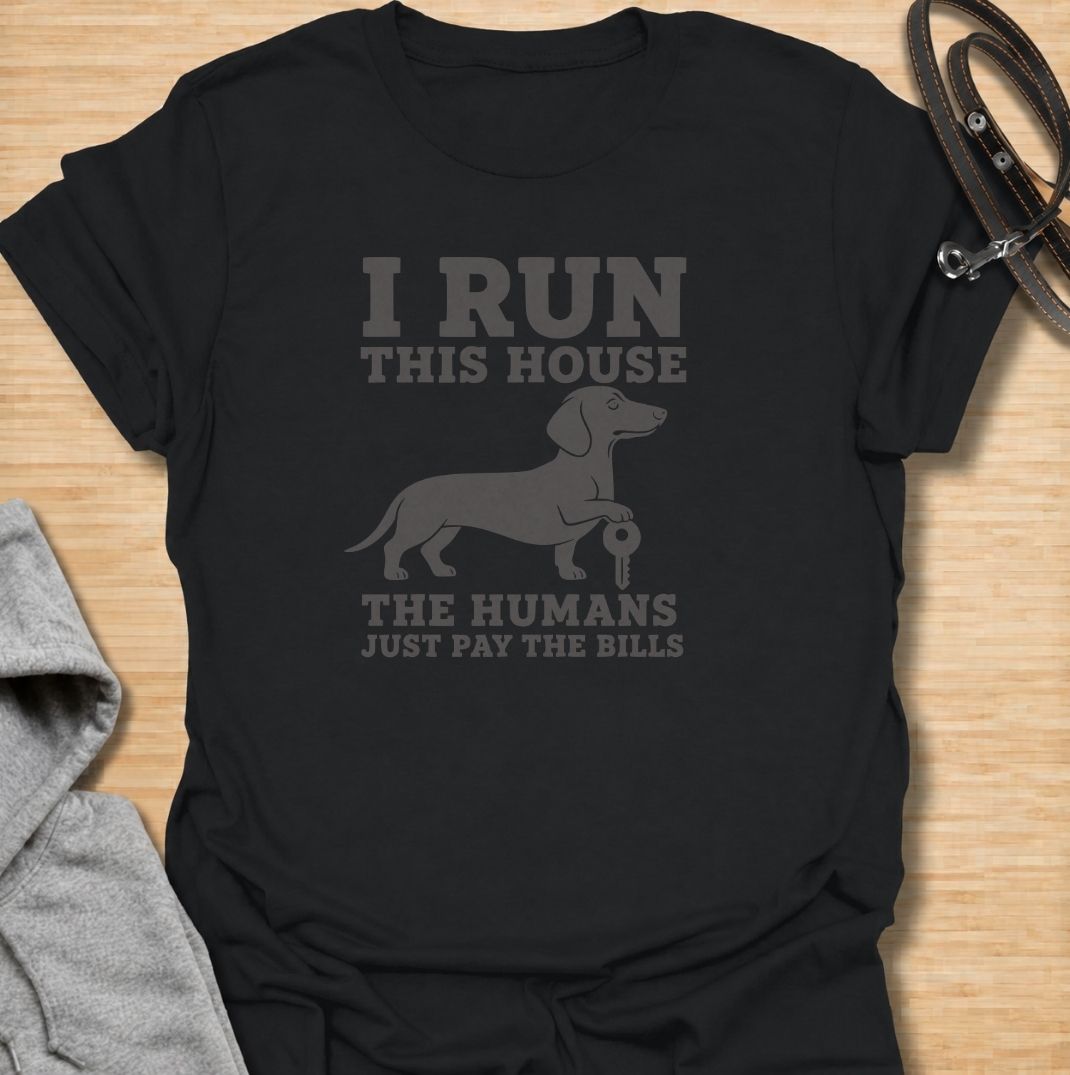 I run this house—the humans just pay the bills. A funny dachshund T-shirt for owners whose confident sausage dog is clearly in charge.