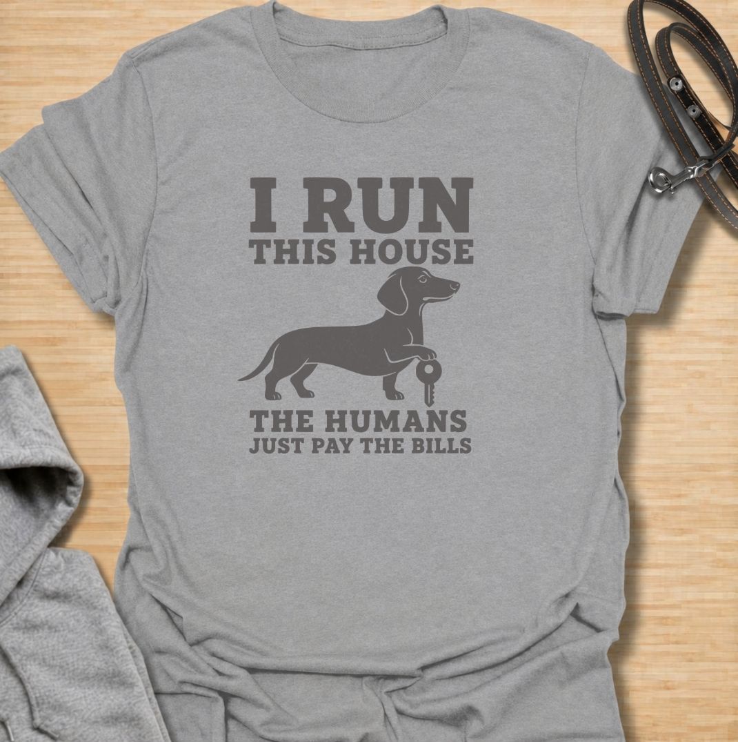 I run this house—the humans just pay the bills. A funny dachshund T-shirt for owners whose confident sausage dog is clearly in charge.