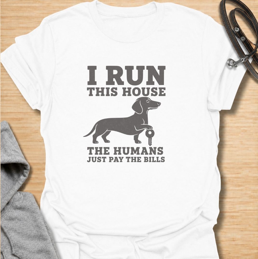 I run this house—the humans just pay the bills. A funny dachshund T-shirt for owners whose confident sausage dog is clearly in charge.