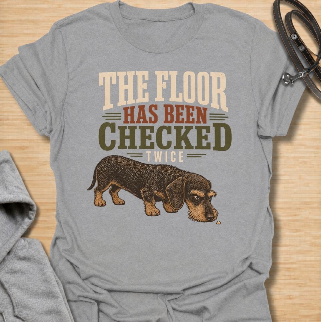 For dachshunds who treat every dropped crumb like an urgent inspection assignment. This funny dachshund T-shirt features the phrase “The Floor Has Been Checked Twice” with a determined little doxie on snack patrol. Perfect for dog owners who know their sausage dog never misses a food-related opportunity. A playful vintage-style dog lover tee that captures classic dachshund greed, focus and personality.