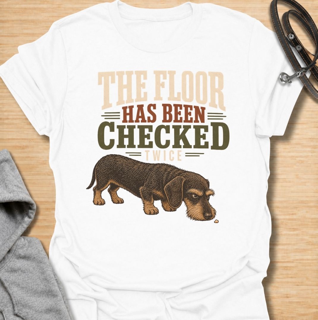 For dachshunds who treat every dropped crumb like an urgent inspection assignment. This funny dachshund T-shirt features the phrase “The Floor Has Been Checked Twice” with a determined little doxie on snack patrol. Perfect for dog owners who know their sausage dog never misses a food-related opportunity. A playful vintage-style dog lover tee that captures classic dachshund greed, focus and personality.