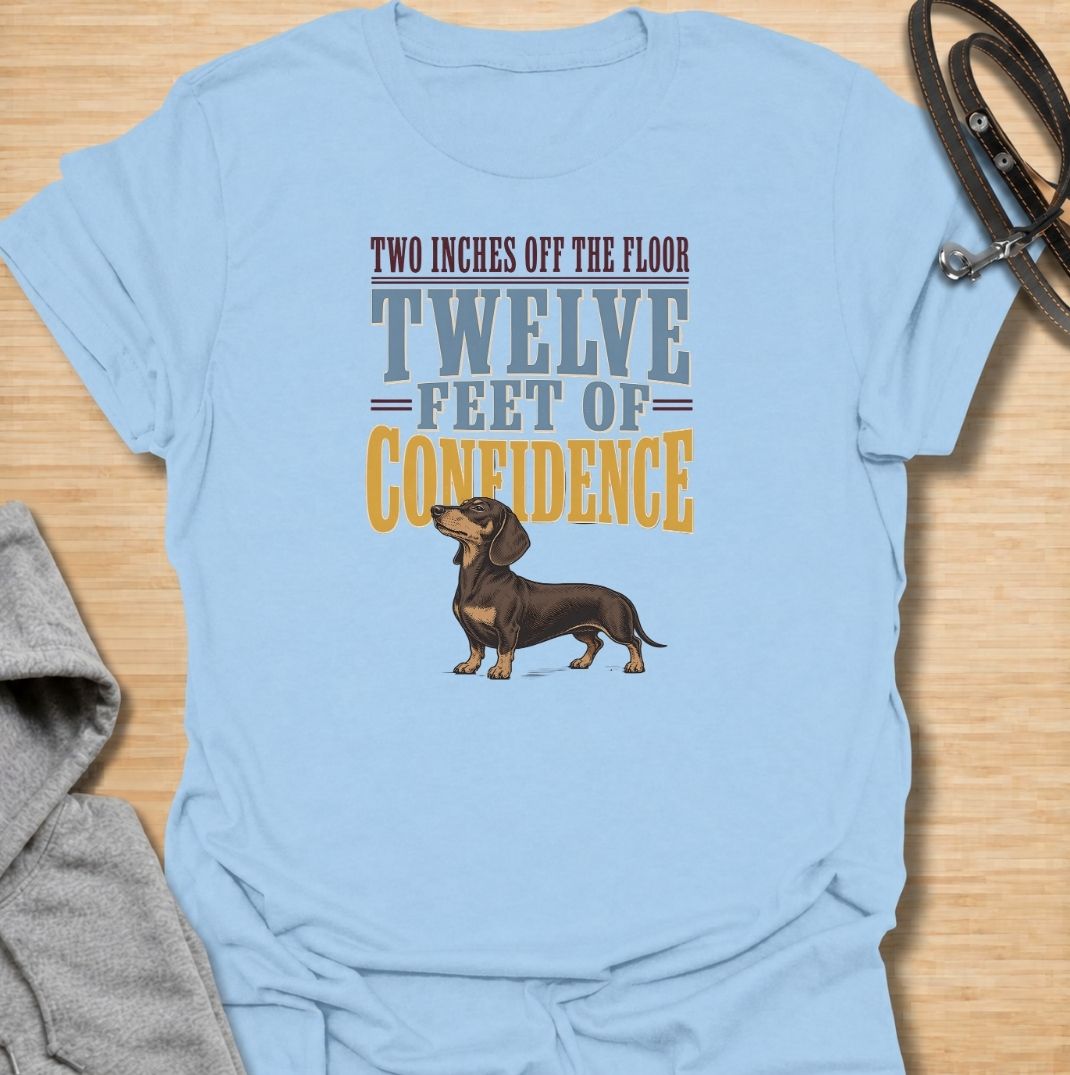 For dachshunds who may only be a couple of inches off the floor but carry themselves like they own the entire room. This funny dachshund T-shirt features the phrase “Two Inches Off the Floor, Twelve Feet of Confidence” with a proud little doxie illustration. Perfect for owners who know tiny legs come with enormous personality, attitude and self-belief. A bold vintage-style dog lover tee made for anyone who lives with a fearless sausage dog.