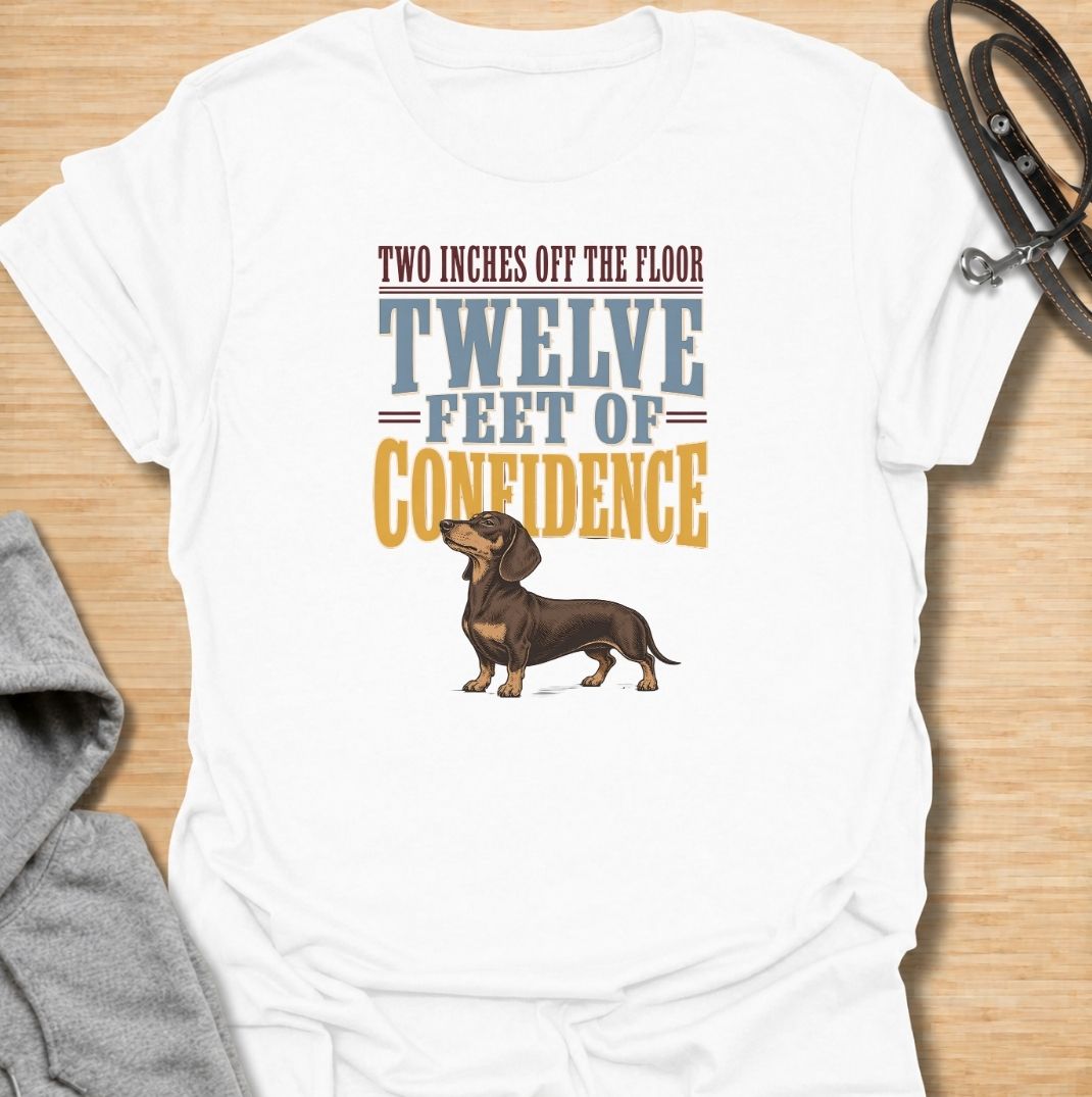 For dachshunds who may only be a couple of inches off the floor but carry themselves like they own the entire room. This funny dachshund T-shirt features the phrase “Two Inches Off the Floor, Twelve Feet of Confidence” with a proud little doxie illustration. Perfect for owners who know tiny legs come with enormous personality, attitude and self-belief. A bold vintage-style dog lover tee made for anyone who lives with a fearless sausage dog.