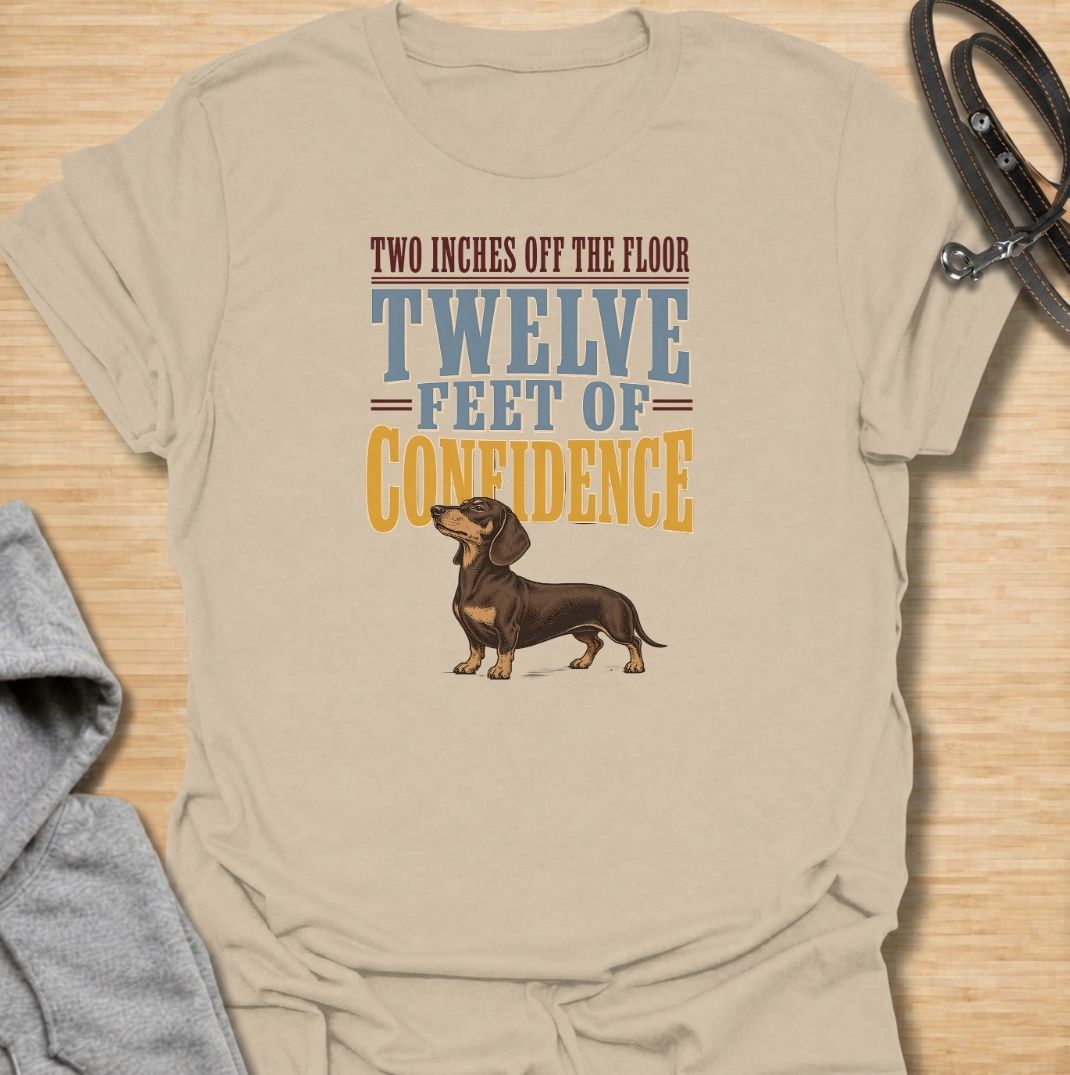 For dachshunds who may only be a couple of inches off the floor but carry themselves like they own the entire room. This funny dachshund T-shirt features the phrase “Two Inches Off the Floor, Twelve Feet of Confidence” with a proud little doxie illustration. Perfect for owners who know tiny legs come with enormous personality, attitude and self-belief. A bold vintage-style dog lover tee made for anyone who lives with a fearless sausage dog.