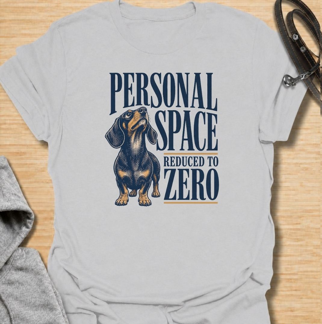 A funny dachshund T-shirt for anyone whose idea of personal space disappeared the moment a dachshund moved in. Featuring the phrase “Personal Space Reduced to Zero” with a bold vintage-style dachshund illustration, this design captures the breed’s famously clingy personality. Perfect for dachshund moms, dachshund dads, sausage dog owners, and anyone who lives with a devoted little shadow. A playful everyday tee for fans of dachshund humor, velcro dogs, and affectionate four-legged companions.