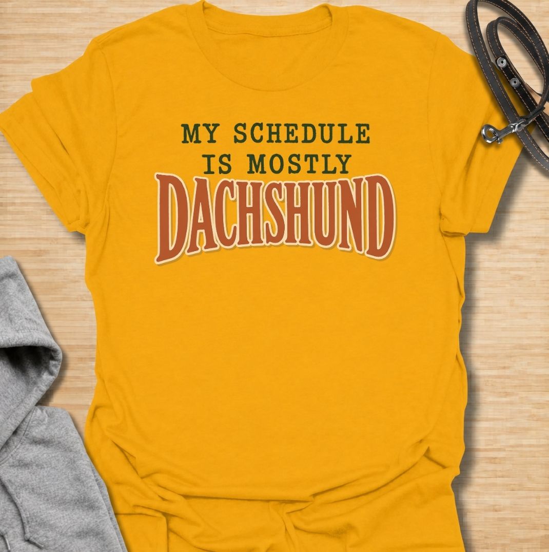 A funny dachshund T-shirt for anyone whose daily plans somehow revolve around their favorite little dog. Featuring the phrase “My Schedule Is Mostly Dachshund” in bold vintage-inspired typography, this design is simple, punchy, and easy to wear. Perfect for dachshund moms, dachshund dads, sausage dog owners, and anyone whose calendar is permanently shaped around walks, cuddles, and dachshund demands. A fun everyday tee for dog lovers who know exactly who really controls the schedule.