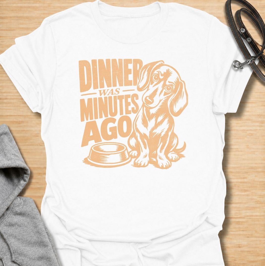 A funny dachshund T-shirt for anyone whose dog believes dinner is always overdue. Featuring the phrase “Dinner Was Minutes Ago” with a hungry-looking dachshund and empty bowl, this design perfectly captures the breed’s dramatic relationship with food. Ideal for dachshund moms, dachshund dads, sausage dog owners, and anyone familiar with the stare that appears five minutes after mealtime. A playful everyday tee for fans of dachshund humor, food-obsessed dogs, and permanently hungry little companions.