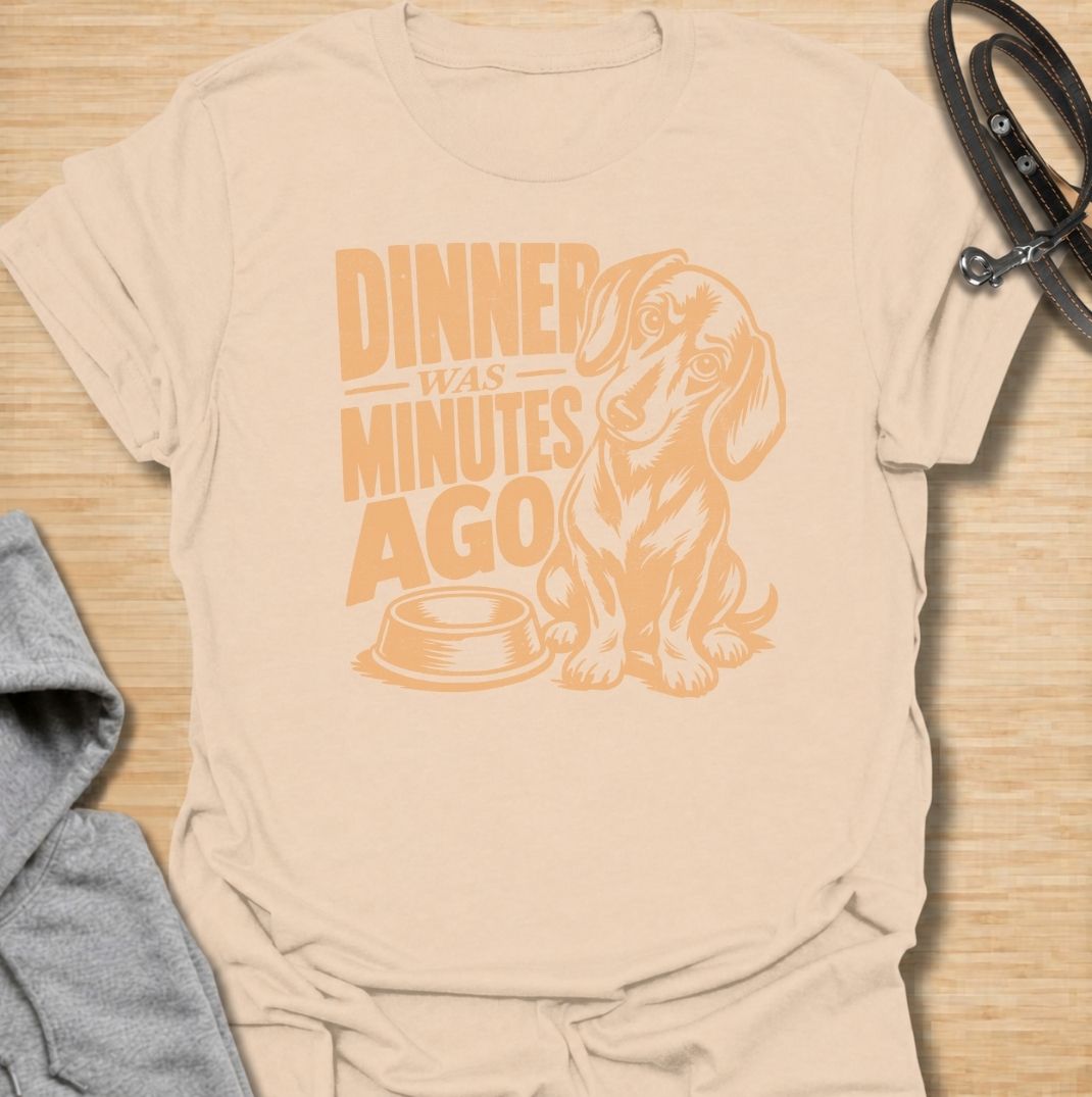 A funny dachshund T-shirt for anyone whose dog believes dinner is always overdue. Featuring the phrase “Dinner Was Minutes Ago” with a hungry-looking dachshund and empty bowl, this design perfectly captures the breed’s dramatic relationship with food. Ideal for dachshund moms, dachshund dads, sausage dog owners, and anyone familiar with the stare that appears five minutes after mealtime. A playful everyday tee for fans of dachshund humor, food-obsessed dogs, and permanently hungry little companions.