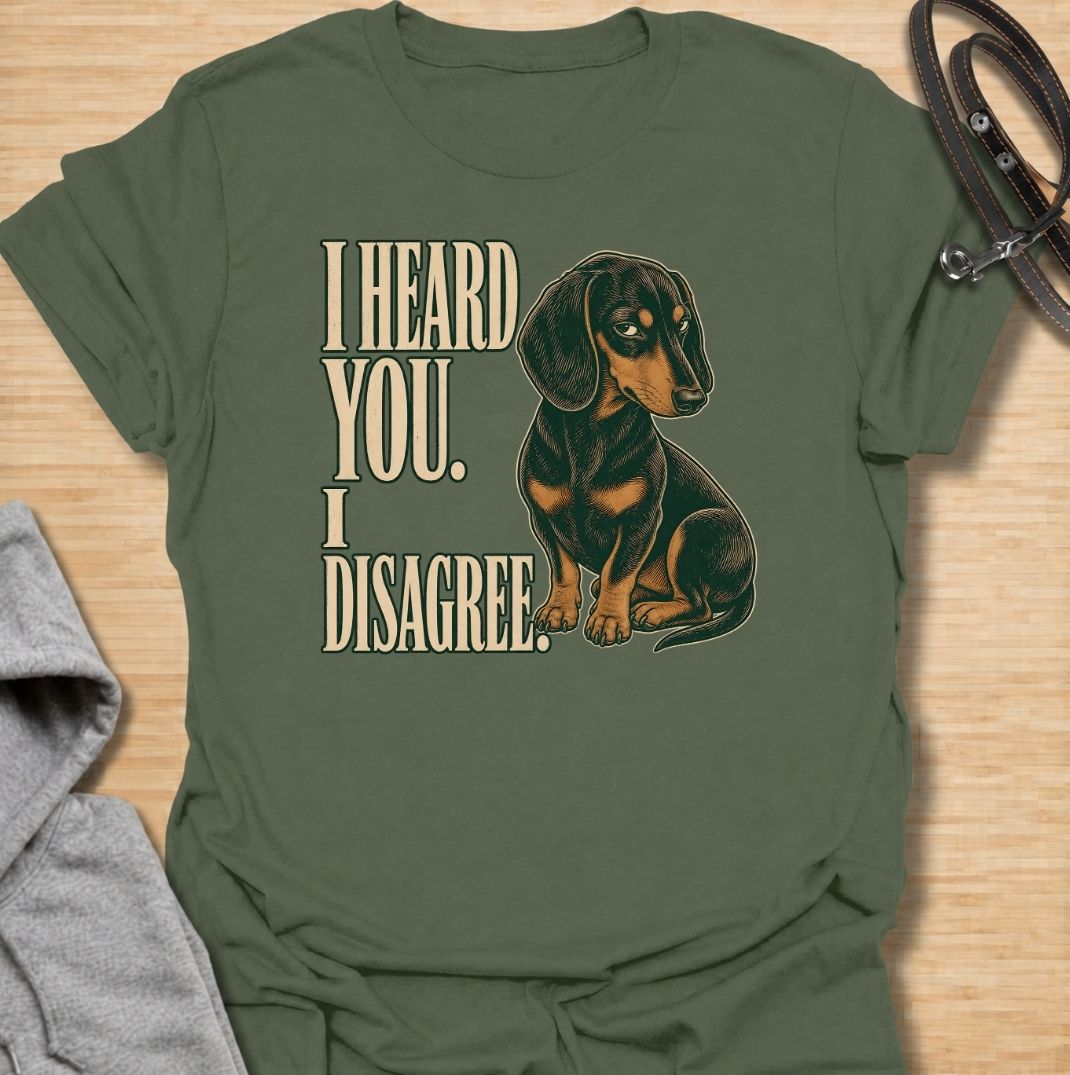 A funny dachshund T-shirt for anyone who knows that hearing a command and agreeing with it are two completely different things. Featuring the phrase “I Heard You. I Disagree.” with a vintage-style dachshund giving the perfect skeptical side-eye, this design captures the breed’s famously stubborn personality. Ideal for dachshund moms, dachshund dads, sausage dog owners, and anyone familiar with selective listening from a determined little dog. A playful everyday tee for fans of dachshund humor, wiener dog at