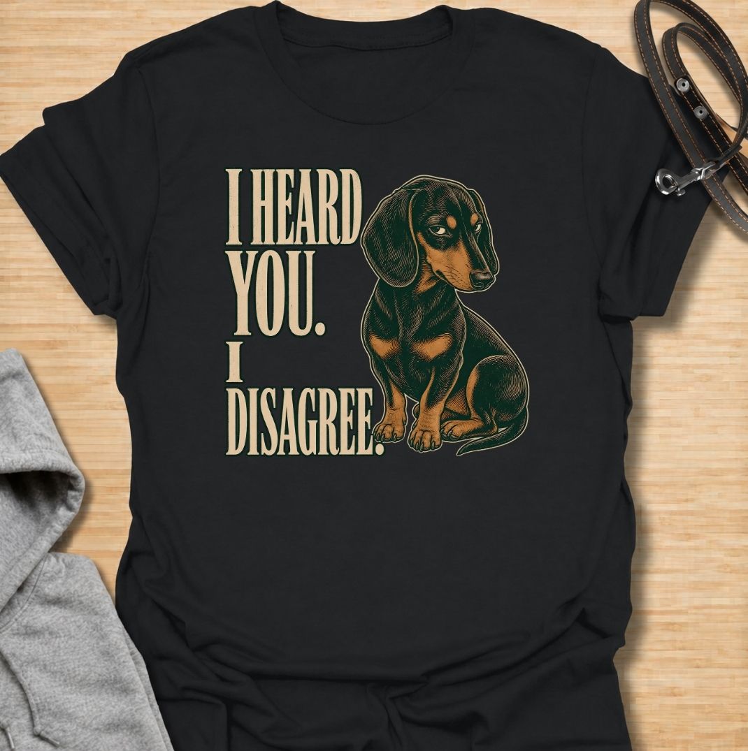 A funny dachshund T-shirt for anyone who knows that hearing a command and agreeing with it are two completely different things. Featuring the phrase “I Heard You. I Disagree.” with a vintage-style dachshund giving the perfect skeptical side-eye, this design captures the breed’s famously stubborn personality. Ideal for dachshund moms, dachshund dads, sausage dog owners, and anyone familiar with selective listening from a determined little dog. A playful everyday tee for fans of dachshund humor, wiener dog at