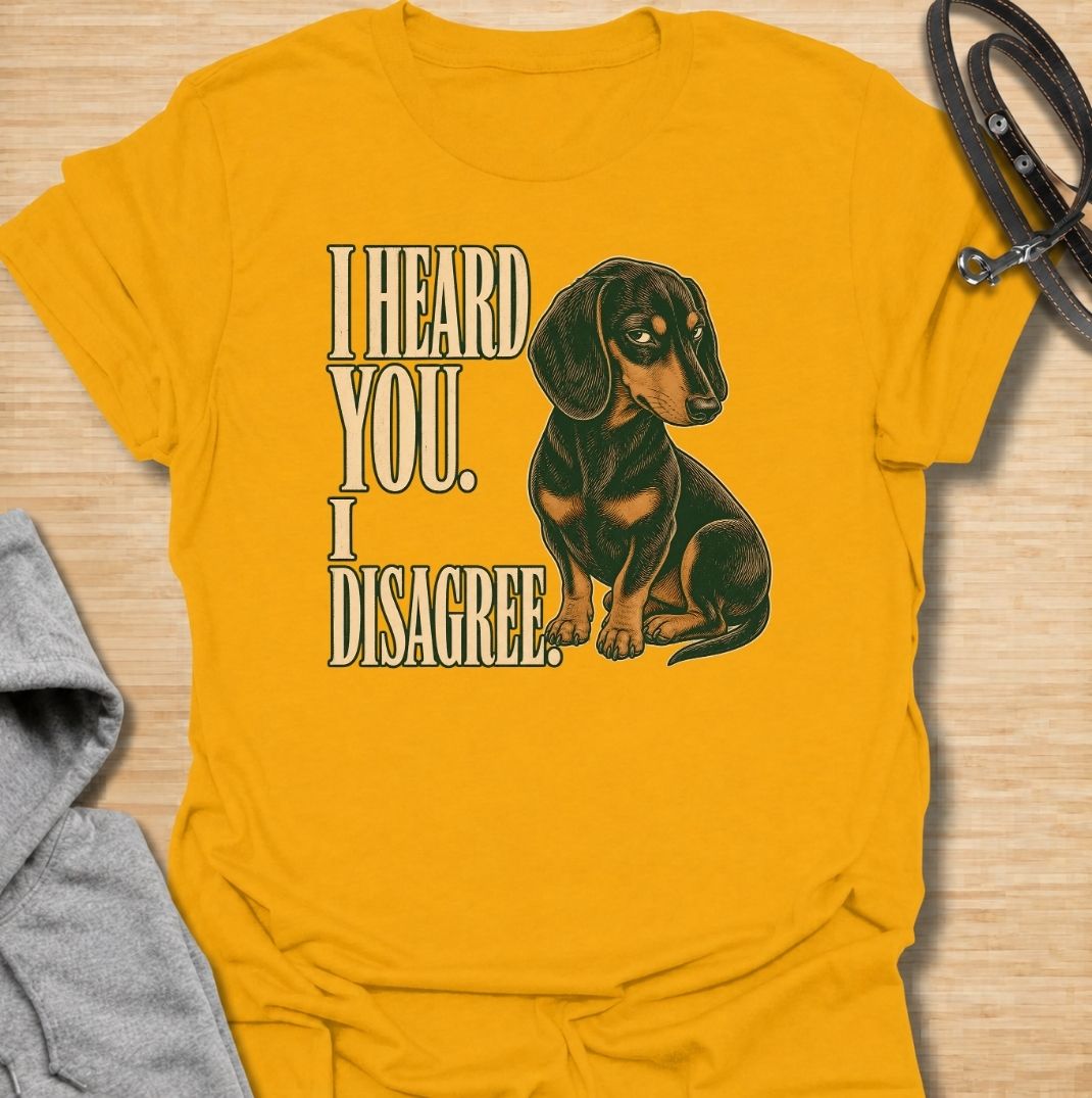 A funny dachshund T-shirt for anyone who knows that hearing a command and agreeing with it are two completely different things. Featuring the phrase “I Heard You. I Disagree.” with a vintage-style dachshund giving the perfect skeptical side-eye, this design captures the breed’s famously stubborn personality. Ideal for dachshund moms, dachshund dads, sausage dog owners, and anyone familiar with selective listening from a determined little dog. A playful everyday tee for fans of dachshund humor, wiener dog at