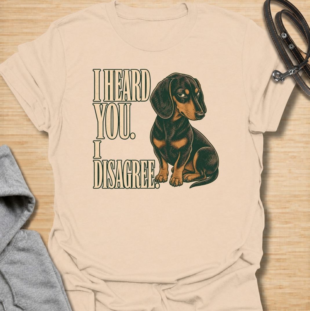 A funny dachshund T-shirt for anyone who knows that hearing a command and agreeing with it are two completely different things. Featuring the phrase “I Heard You. I Disagree.” with a vintage-style dachshund giving the perfect skeptical side-eye, this design captures the breed’s famously stubborn personality. Ideal for dachshund moms, dachshund dads, sausage dog owners, and anyone familiar with selective listening from a determined little dog. A playful everyday tee for fans of dachshund humor, wiener dog at