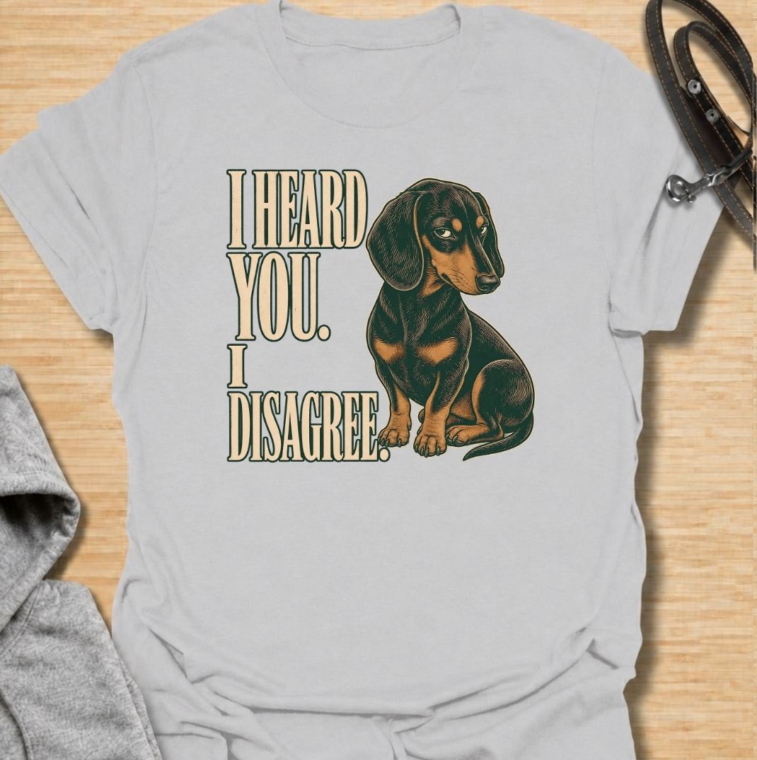 A funny dachshund T-shirt for anyone who knows that hearing a command and agreeing with it are two completely different things. Featuring the phrase “I Heard You. I Disagree.” with a vintage-style dachshund giving the perfect skeptical side-eye, this design captures the breed’s famously stubborn personality. Ideal for dachshund moms, dachshund dads, sausage dog owners, and anyone familiar with selective listening from a determined little dog. A playful everyday tee for fans of dachshund humor, wiener dog at