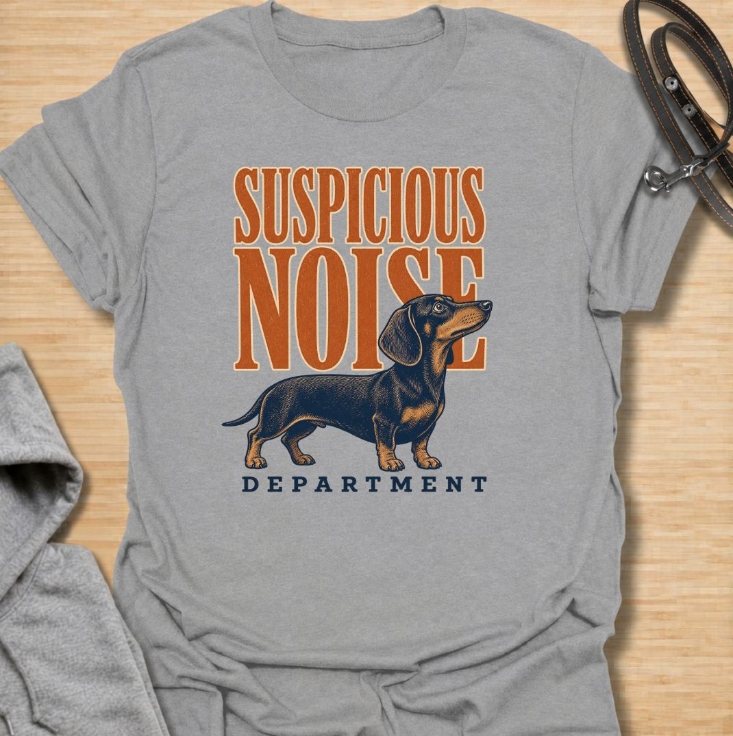 A funny dachshund T-shirt for anyone whose dog treats every unexpected sound like an urgent investigation. Featuring the phrase “Suspicious Noise Department” with a watchful dachshund illustration, this design captures the breed’s alert, curious, and slightly dramatic personality. Perfect for dachshund moms, dachshund dads, sausage dog owners, and anyone familiar with barking at absolutely nothing. A playful everyday tee for fans of dachshund humor, watchdog jokes, and breed-specific dog gifts.