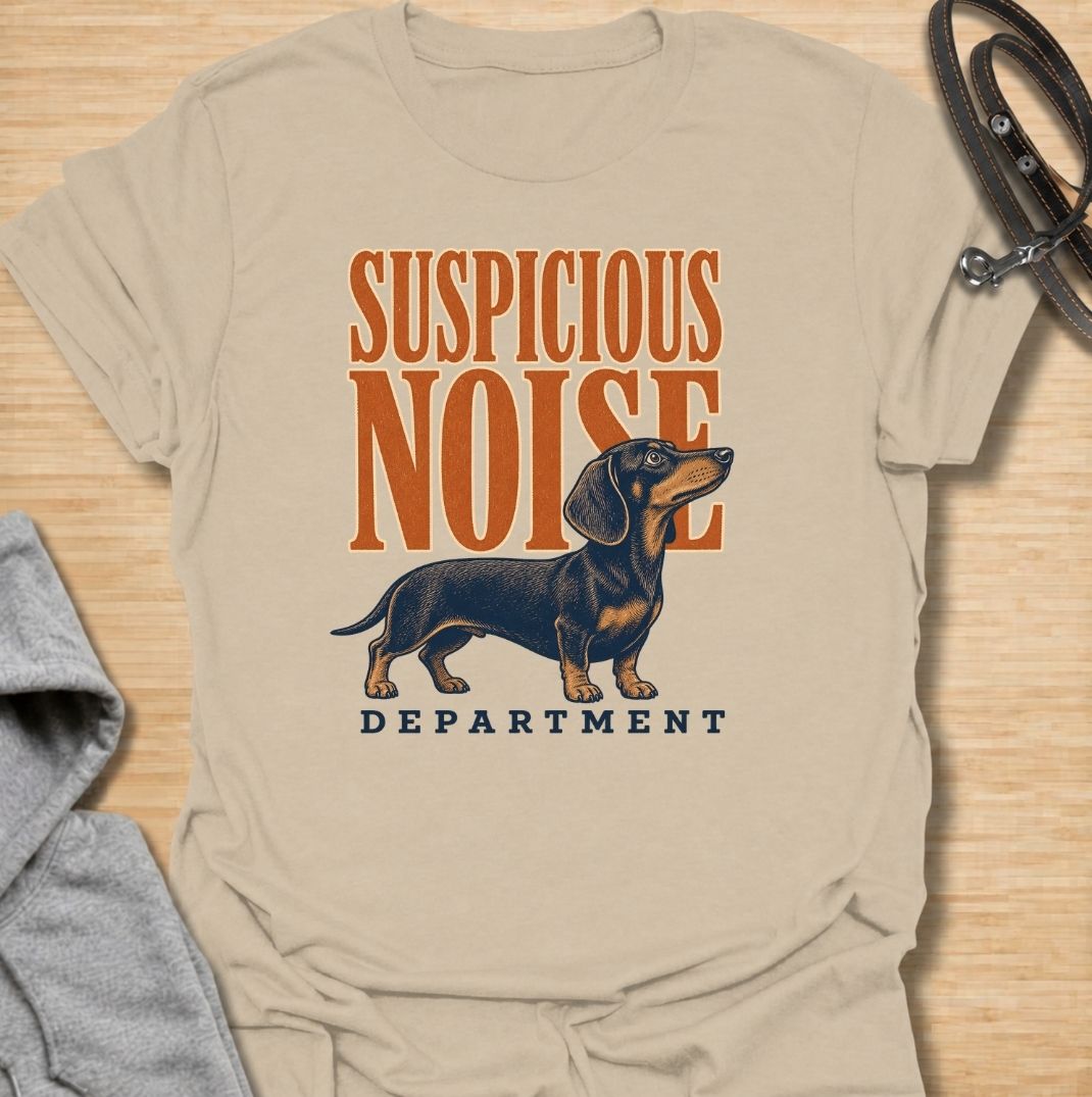 A funny dachshund T-shirt for anyone whose dog treats every unexpected sound like an urgent investigation. Featuring the phrase “Suspicious Noise Department” with a watchful dachshund illustration, this design captures the breed’s alert, curious, and slightly dramatic personality. Perfect for dachshund moms, dachshund dads, sausage dog owners, and anyone familiar with barking at absolutely nothing. A playful everyday tee for fans of dachshund humor, watchdog jokes, and breed-specific dog gifts.
