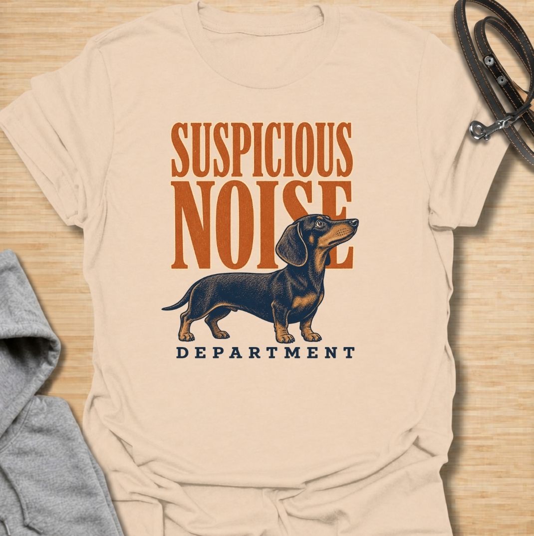 A funny dachshund T-shirt for anyone whose dog treats every unexpected sound like an urgent investigation. Featuring the phrase “Suspicious Noise Department” with a watchful dachshund illustration, this design captures the breed’s alert, curious, and slightly dramatic personality. Perfect for dachshund moms, dachshund dads, sausage dog owners, and anyone familiar with barking at absolutely nothing. A playful everyday tee for fans of dachshund humor, watchdog jokes, and breed-specific dog gifts.