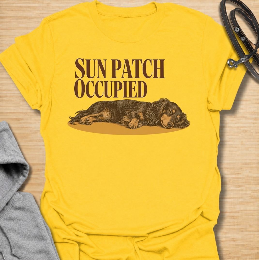 A funny dachshund T-shirt for anyone who knows the best sunny spot in the house is already taken. Featuring the phrase “Sun Patch Occupied” with a relaxed dachshund stretched out in the warmth, this design captures one of the breed’s most familiar little habits. Perfect for dachshund moms, dachshund dads, sausage dog owners, and anyone whose dog follows every patch of sunshine around the room. A cozy everyday tee for fans of dachshund humor, sleepy dogs, and breed-specific gifts.