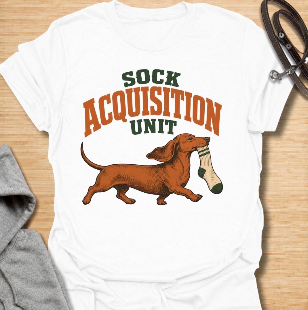 A funny dachshund T-shirt for anyone whose socks mysteriously disappear whenever their dog is nearby. Featuring the phrase “Sock Acquisition Unit” with a proud dachshund carrying its latest prize, this design captures one of those mischievous little habits dog owners know all too well. Perfect for dachshund moms, dachshund dads, sausage dog owners, and anyone living with a determined sock thief. A playful everyday tee for fans of dachshund humor, wiener dogs, and breed-specific dog gifts.