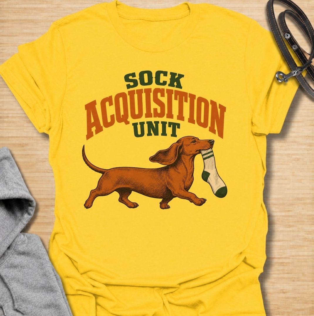 A funny dachshund T-shirt for anyone whose socks mysteriously disappear whenever their dog is nearby. Featuring the phrase “Sock Acquisition Unit” with a proud dachshund carrying its latest prize, this design captures one of those mischievous little habits dog owners know all too well. Perfect for dachshund moms, dachshund dads, sausage dog owners, and anyone living with a determined sock thief. A playful everyday tee for fans of dachshund humor, wiener dogs, and breed-specific dog gifts.