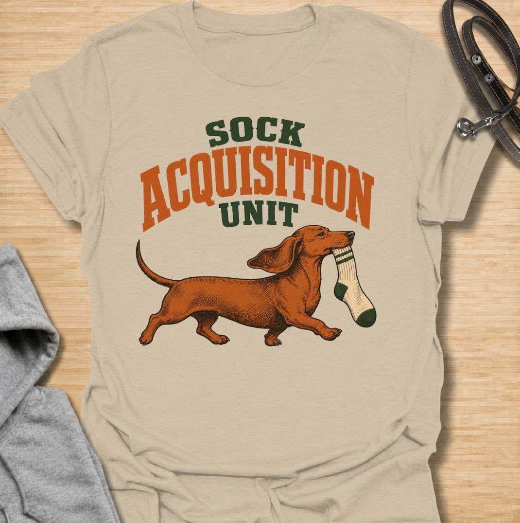 A funny dachshund T-shirt for anyone whose socks mysteriously disappear whenever their dog is nearby. Featuring the phrase “Sock Acquisition Unit” with a proud dachshund carrying its latest prize, this design captures one of those mischievous little habits dog owners know all too well. Perfect for dachshund moms, dachshund dads, sausage dog owners, and anyone living with a determined sock thief. A playful everyday tee for fans of dachshund humor, wiener dogs, and breed-specific dog gifts.