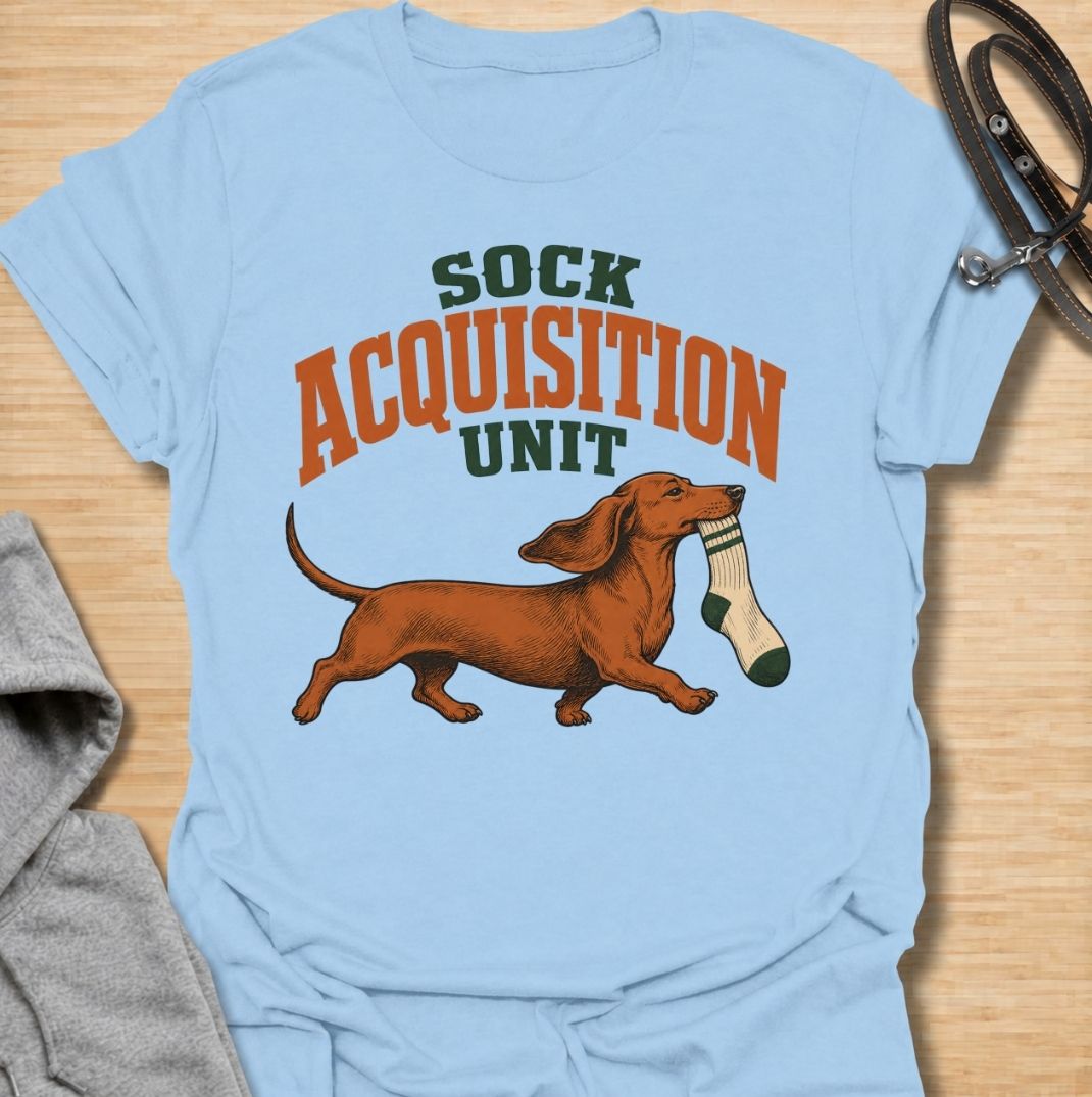A funny dachshund T-shirt for anyone whose socks mysteriously disappear whenever their dog is nearby. Featuring the phrase “Sock Acquisition Unit” with a proud dachshund carrying its latest prize, this design captures one of those mischievous little habits dog owners know all too well. Perfect for dachshund moms, dachshund dads, sausage dog owners, and anyone living with a determined sock thief. A playful everyday tee for fans of dachshund humor, wiener dogs, and breed-specific dog gifts.