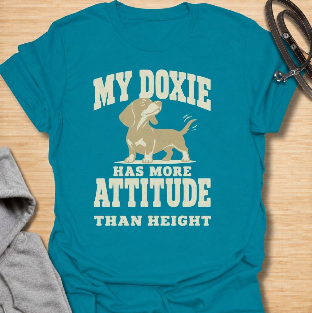 A funny dachshund T-shirt for anyone who knows these little dogs make up for their short legs with an enormous personality. Featuring the phrase “My Doxie Has More Attitude Than Height” with a confident dachshund graphic, this design captures the breed’s bold, stubborn charm perfectly. Ideal for dachshund moms, dachshund dads, sausage dog owners, and anyone who lives with a small dog who thinks big. A playful everyday tee for fans of dachshund humor, doxie attitude, and breed-specific dog gifts.