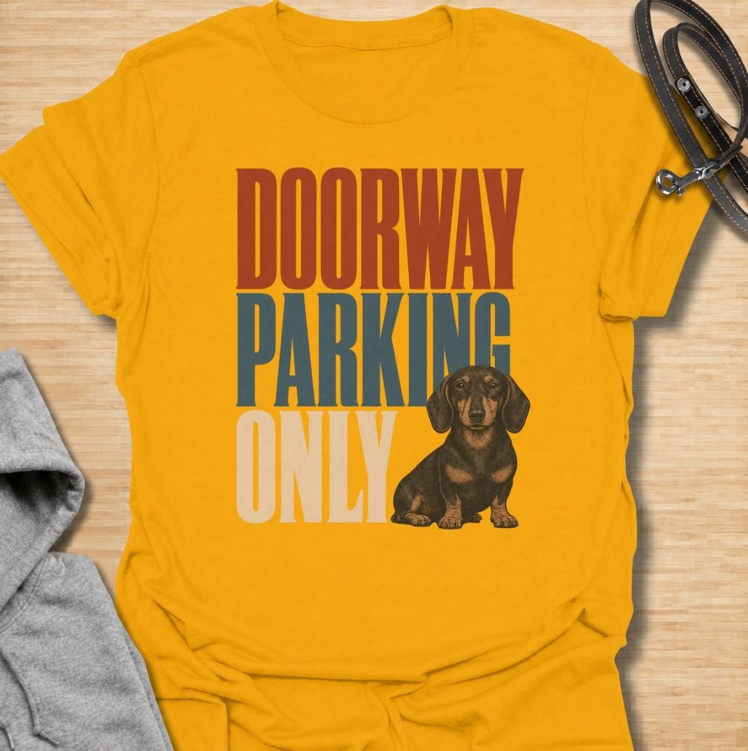 A funny dachshund T-shirt for anyone who knows these little dogs have a talent for stopping exactly where you need to walk. Featuring the phrase “Doorway Parking Only” with a seated dachshund graphic, this design captures one of those everyday breed habits owners instantly recognize. Perfect for dachshund moms, dachshund dads, sausage dog owners, and anyone who regularly finds their path blocked by a very small dog. A playful everyday tee for fans of dachshund humor, doxies, and breed-specific dog gifts.