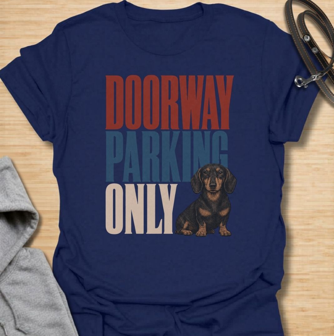A funny dachshund T-shirt for anyone who knows these little dogs have a talent for stopping exactly where you need to walk. Featuring the phrase “Doorway Parking Only” with a seated dachshund graphic, this design captures one of those everyday breed habits owners instantly recognize. Perfect for dachshund moms, dachshund dads, sausage dog owners, and anyone who regularly finds their path blocked by a very small dog. A playful everyday tee for fans of dachshund humor, doxies, and breed-specific dog gifts.
