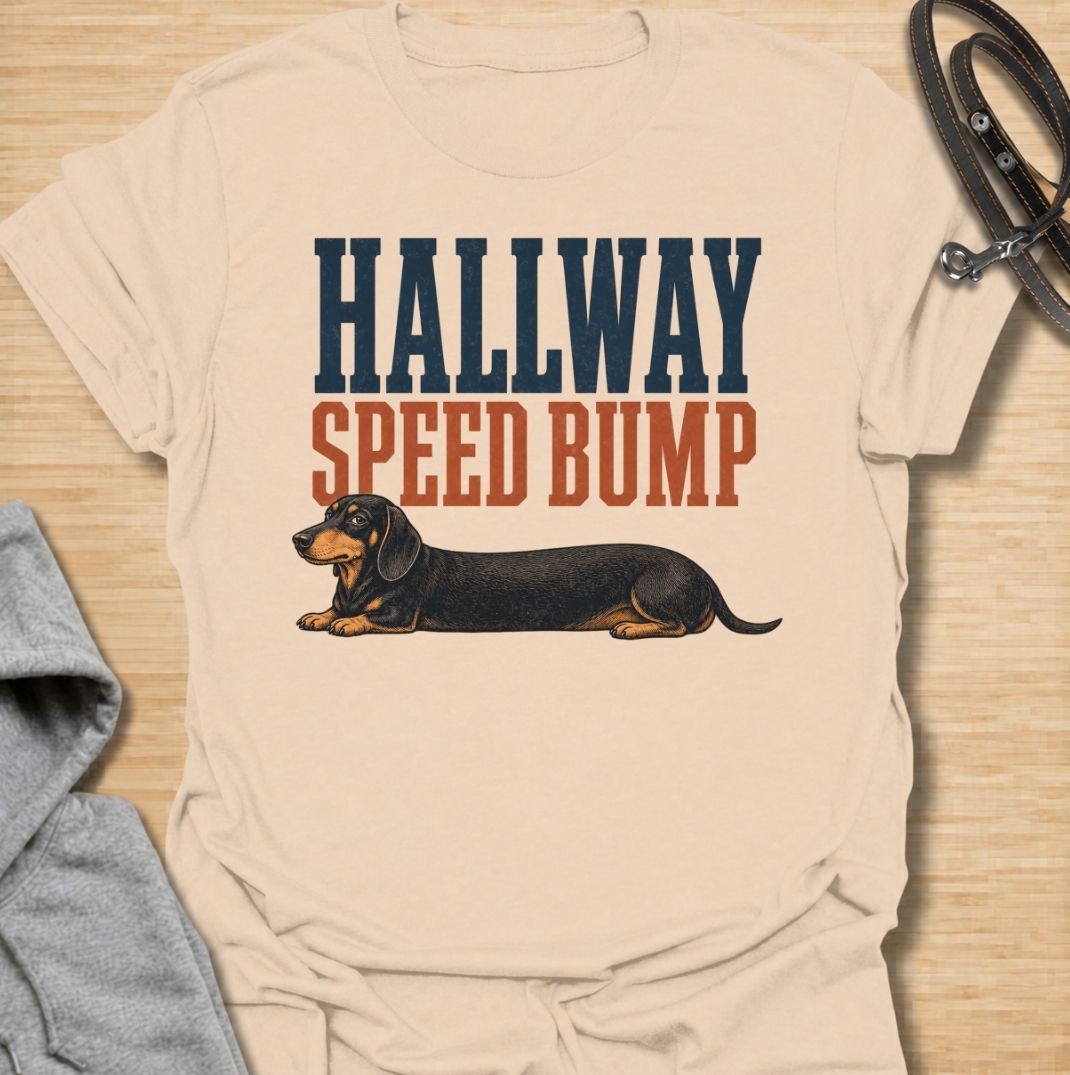 A funny dachshund T-shirt for anyone who knows the hallway is rarely clear when a sausage dog is around. Featuring the phrase “Hallway Speed Bump” with a dachshund stretched out across the floor, this design turns a familiar breed habit into a dry visual joke. Perfect for dachshund moms, dachshund dads, wiener dog owners, and anyone who regularly has to step over their dog at home. A playful everyday tee for fans of dachshund humor, long dogs, and breed-specific dog gifts.