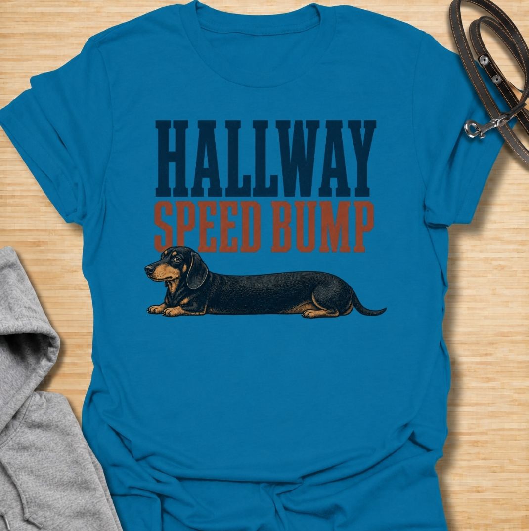 A funny dachshund T-shirt for anyone who knows the hallway is rarely clear when a sausage dog is around. Featuring the phrase “Hallway Speed Bump” with a dachshund stretched out across the floor, this design turns a familiar breed habit into a dry visual joke. Perfect for dachshund moms, dachshund dads, wiener dog owners, and anyone who regularly has to step over their dog at home. A playful everyday tee for fans of dachshund humor, long dogs, and breed-specific dog gifts.