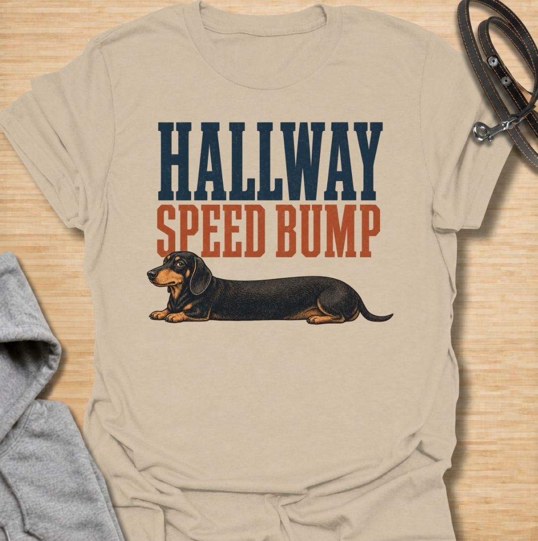 A funny dachshund T-shirt for anyone who knows the hallway is rarely clear when a sausage dog is around. Featuring the phrase “Hallway Speed Bump” with a dachshund stretched out across the floor, this design turns a familiar breed habit into a dry visual joke. Perfect for dachshund moms, dachshund dads, wiener dog owners, and anyone who regularly has to step over their dog at home. A playful everyday tee for fans of dachshund humor, long dogs, and breed-specific dog gifts.