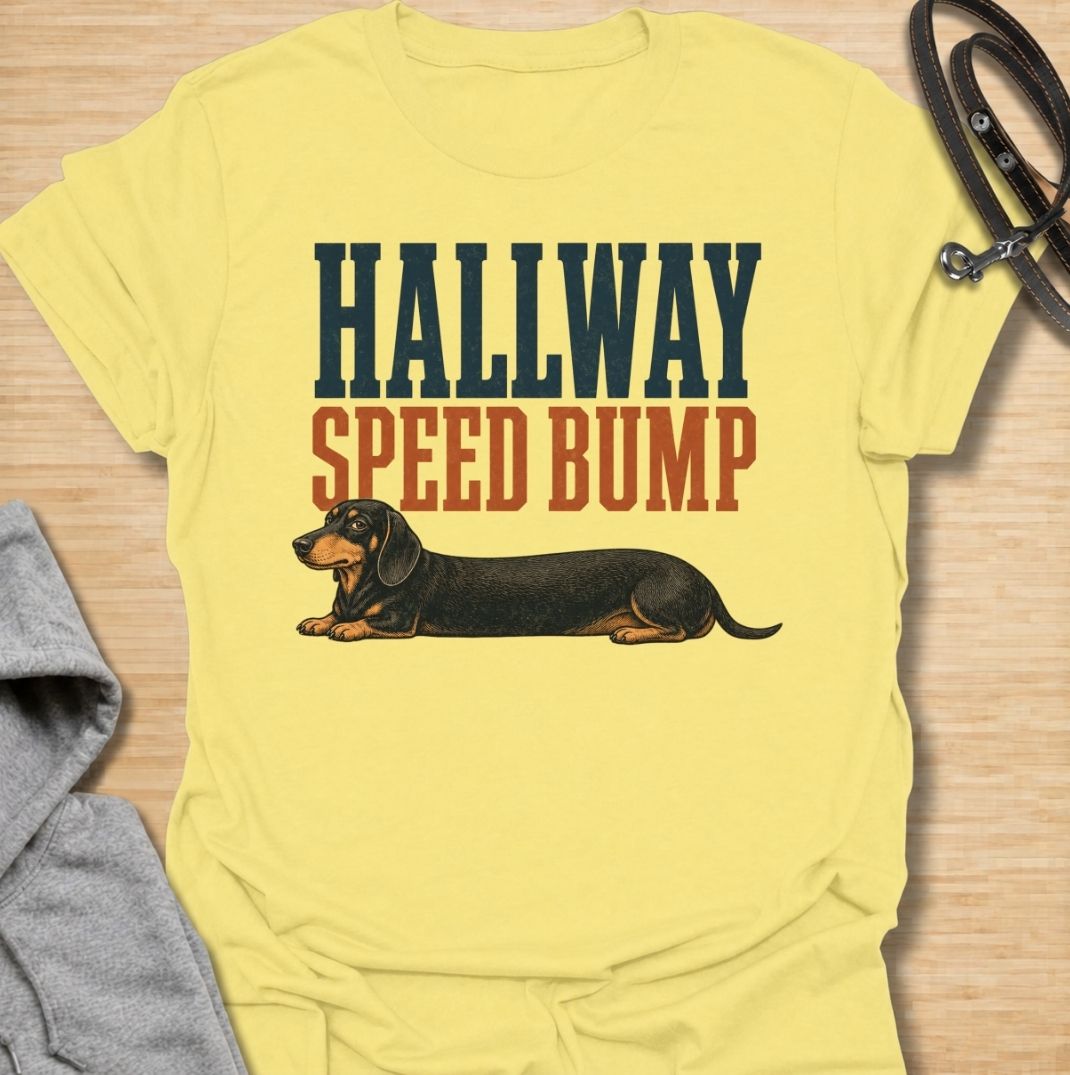 A funny dachshund T-shirt for anyone who knows the hallway is rarely clear when a sausage dog is around. Featuring the phrase “Hallway Speed Bump” with a dachshund stretched out across the floor, this design turns a familiar breed habit into a dry visual joke. Perfect for dachshund moms, dachshund dads, wiener dog owners, and anyone who regularly has to step over their dog at home. A playful everyday tee for fans of dachshund humor, long dogs, and breed-specific dog gifts.