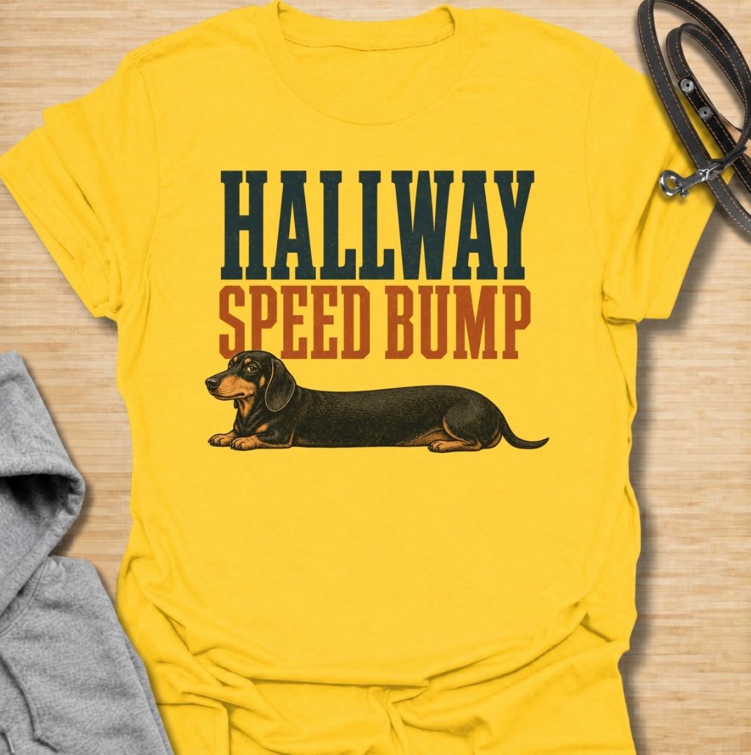 A funny dachshund T-shirt for anyone who knows the hallway is rarely clear when a sausage dog is around. Featuring the phrase “Hallway Speed Bump” with a dachshund stretched out across the floor, this design turns a familiar breed habit into a dry visual joke. Perfect for dachshund moms, dachshund dads, wiener dog owners, and anyone who regularly has to step over their dog at home. A playful everyday tee for fans of dachshund humor, long dogs, and breed-specific dog gifts.