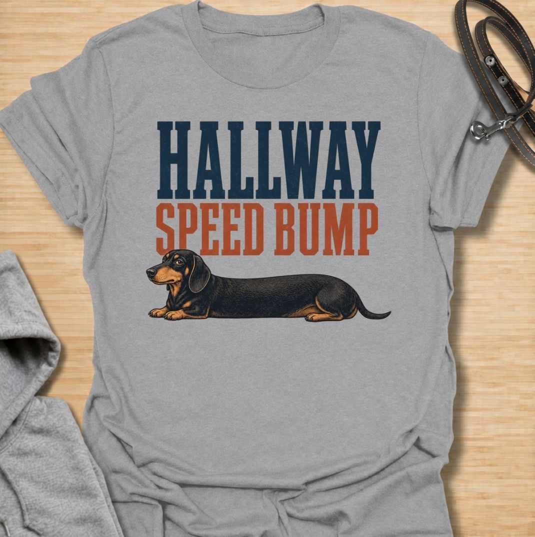 A funny dachshund T-shirt for anyone who knows the hallway is rarely clear when a sausage dog is around. Featuring the phrase “Hallway Speed Bump” with a dachshund stretched out across the floor, this design turns a familiar breed habit into a dry visual joke. Perfect for dachshund moms, dachshund dads, wiener dog owners, and anyone who regularly has to step over their dog at home. A playful everyday tee for fans of dachshund humor, long dogs, and breed-specific dog gifts.