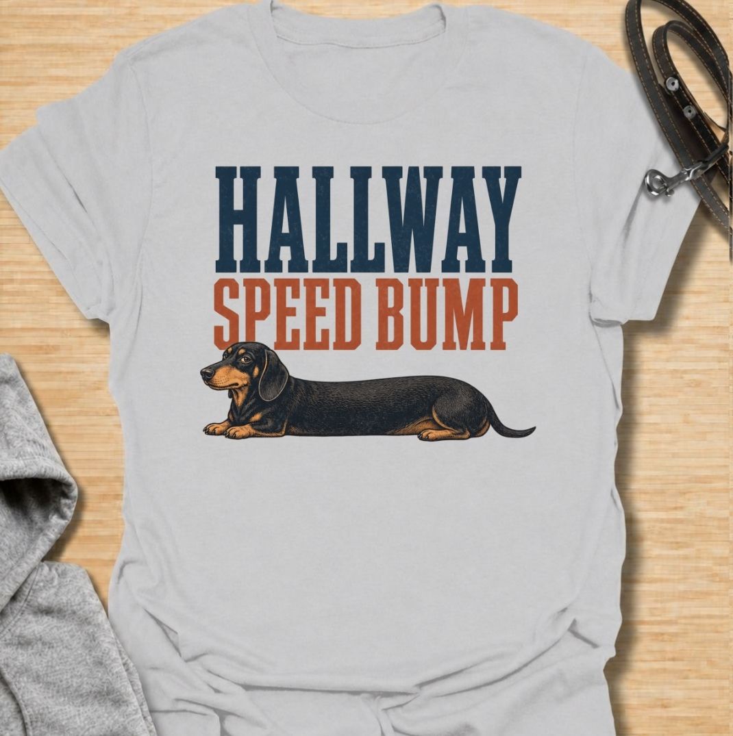A funny dachshund T-shirt for anyone who knows the hallway is rarely clear when a sausage dog is around. Featuring the phrase “Hallway Speed Bump” with a dachshund stretched out across the floor, this design turns a familiar breed habit into a dry visual joke. Perfect for dachshund moms, dachshund dads, wiener dog owners, and anyone who regularly has to step over their dog at home. A playful everyday tee for fans of dachshund humor, long dogs, and breed-specific dog gifts.