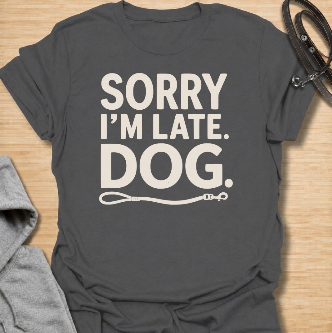 A funny dog T-shirt for anyone whose schedule is regularly dictated by walks, sniffing stops, and a four-legged companion. Featuring the phrase “Sorry I’m Late. Dog.” with a simple leash graphic, this design delivers dry, relatable dog-owner humor in a clean text-based style. Perfect for dog moms, dog dads, rescue dog owners, and anyone who has ever blamed their lateness on the dog. A playful everyday tee for fans of funny dog sayings, pet parent humor, and general dog lover gifts.