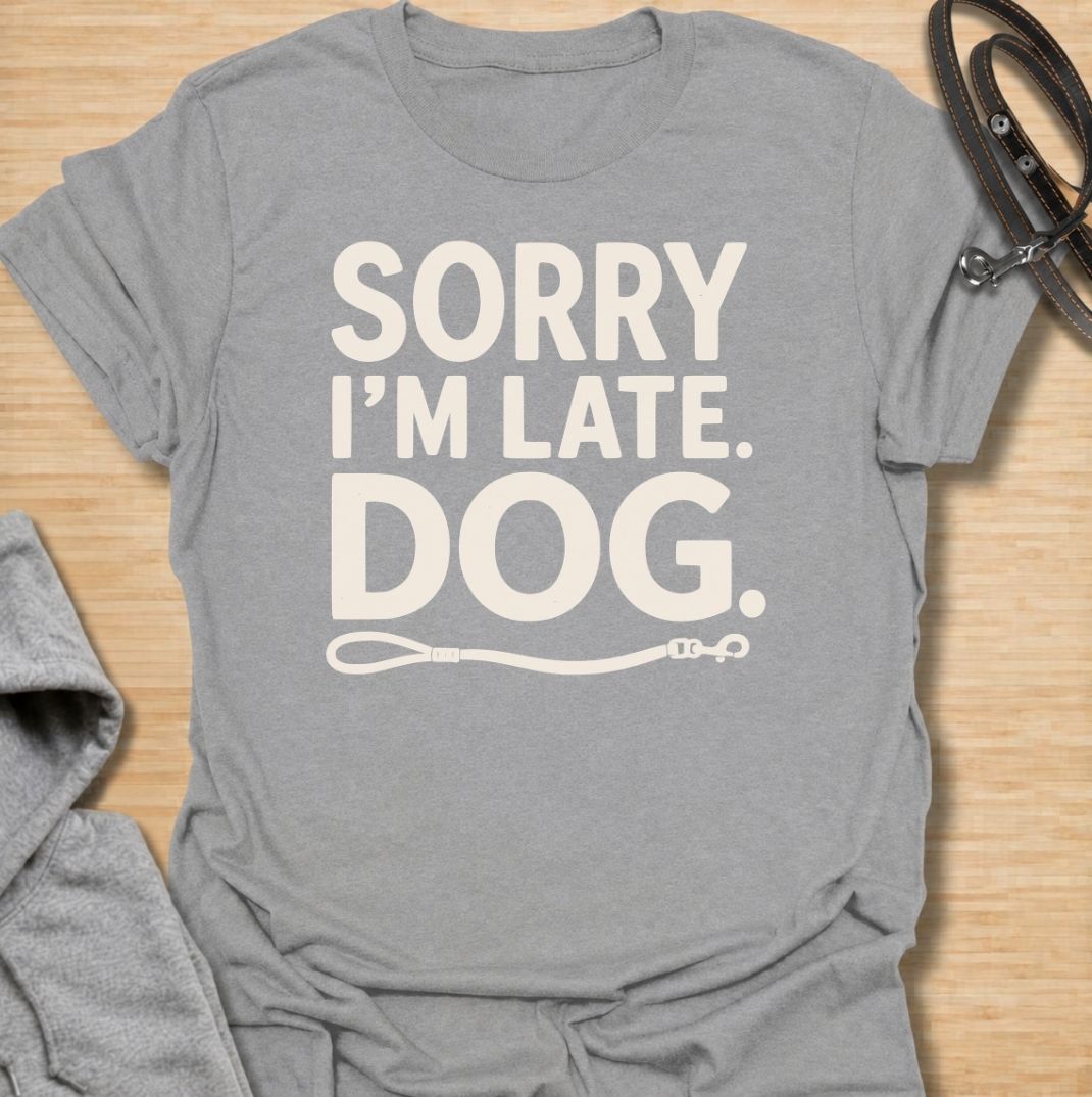 A funny dog T-shirt for anyone whose schedule is regularly dictated by walks, sniffing stops, and a four-legged companion. Featuring the phrase “Sorry I’m Late. Dog.” with a simple leash graphic, this design delivers dry, relatable dog-owner humor in a clean text-based style. Perfect for dog moms, dog dads, rescue dog owners, and anyone who has ever blamed their lateness on the dog. A playful everyday tee for fans of funny dog sayings, pet parent humor, and general dog lover gifts.