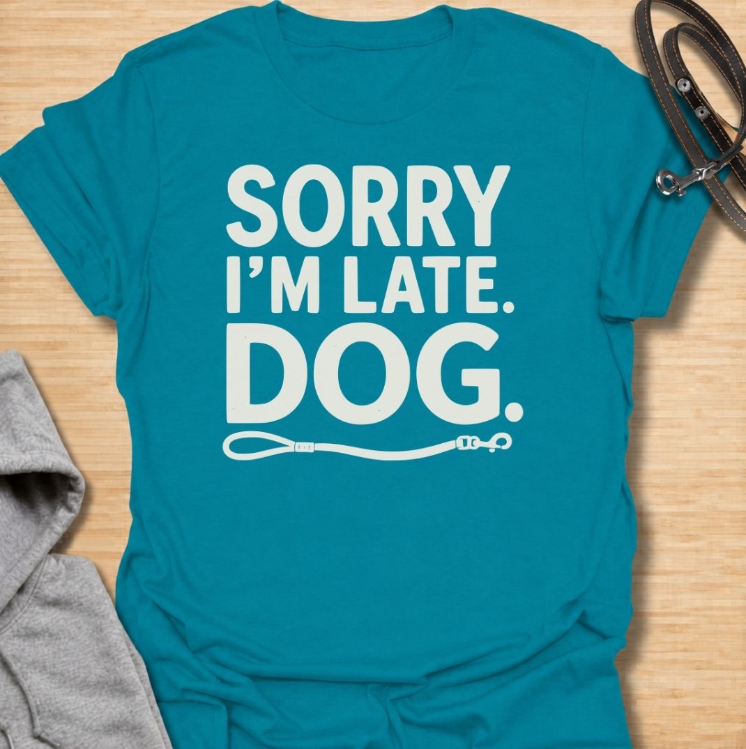 A funny dog T-shirt for anyone whose schedule is regularly dictated by walks, sniffing stops, and a four-legged companion. Featuring the phrase “Sorry I’m Late. Dog.” with a simple leash graphic, this design delivers dry, relatable dog-owner humor in a clean text-based style. Perfect for dog moms, dog dads, rescue dog owners, and anyone who has ever blamed their lateness on the dog. A playful everyday tee for fans of funny dog sayings, pet parent humor, and general dog lover gifts.