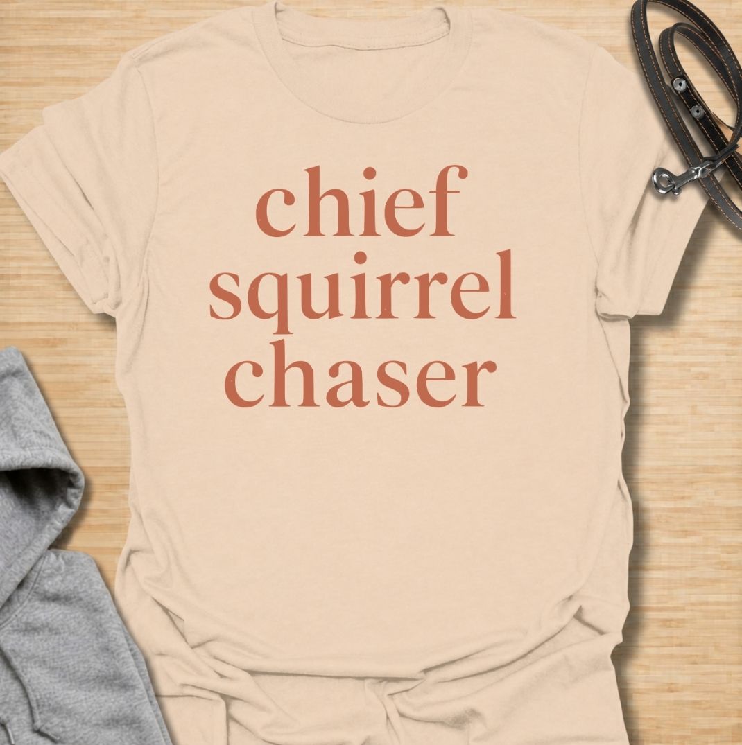 A funny dog T-shirt for anyone whose dog takes squirrel patrol very seriously. Featuring the phrase “Chief Squirrel Chaser” in a clean, bold text-only design, this shirt is perfect for dogs who treat every backyard visitor like an emergency. Ideal for dog moms, dog dads, rescue dog owners, and anyone familiar with sudden squirrel-fueled chaos. A simple everyday tee for fans of dog humor, playful pet sayings, and general dog lover gifts.